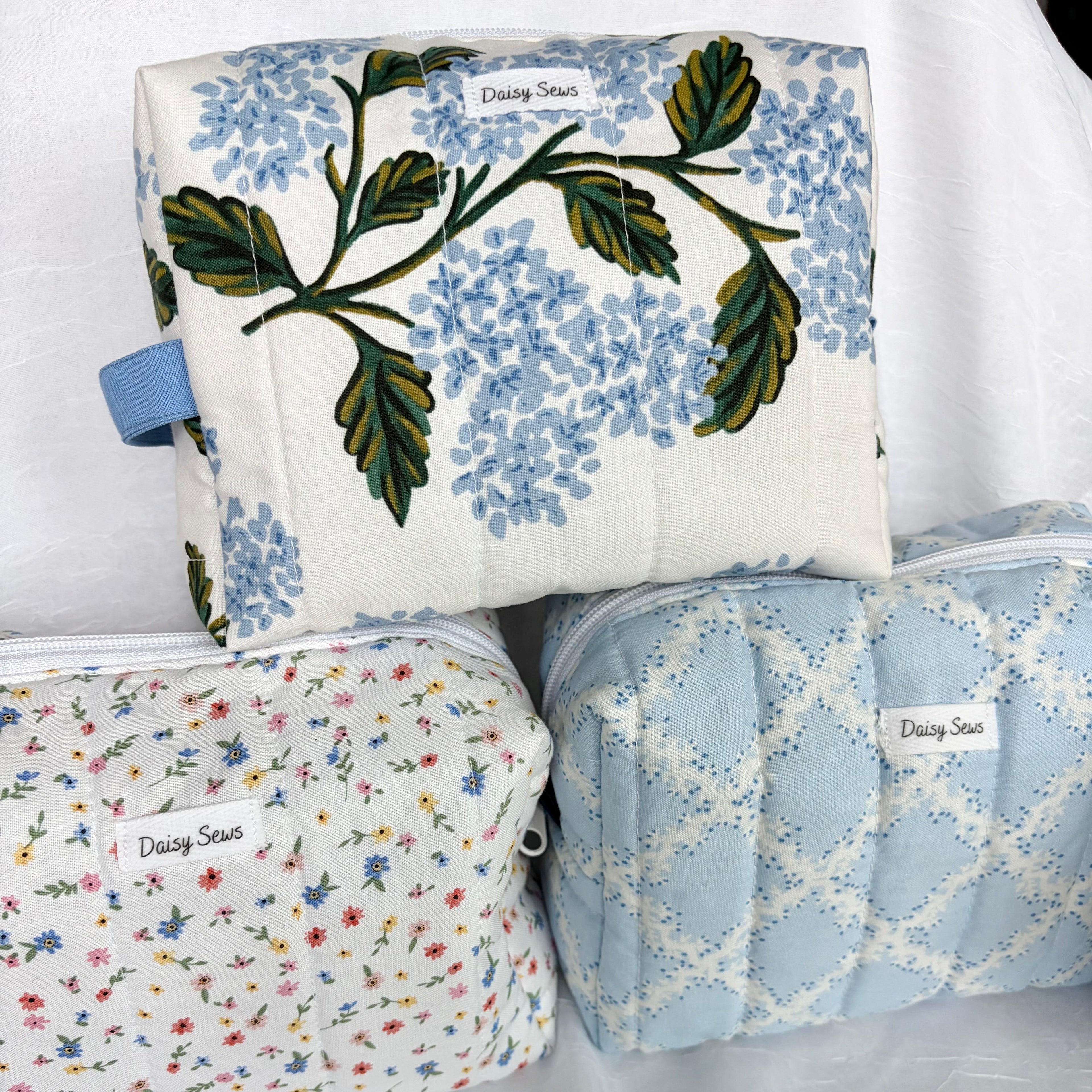 pyramid of three toiletry bags  in cool blue tones with florals