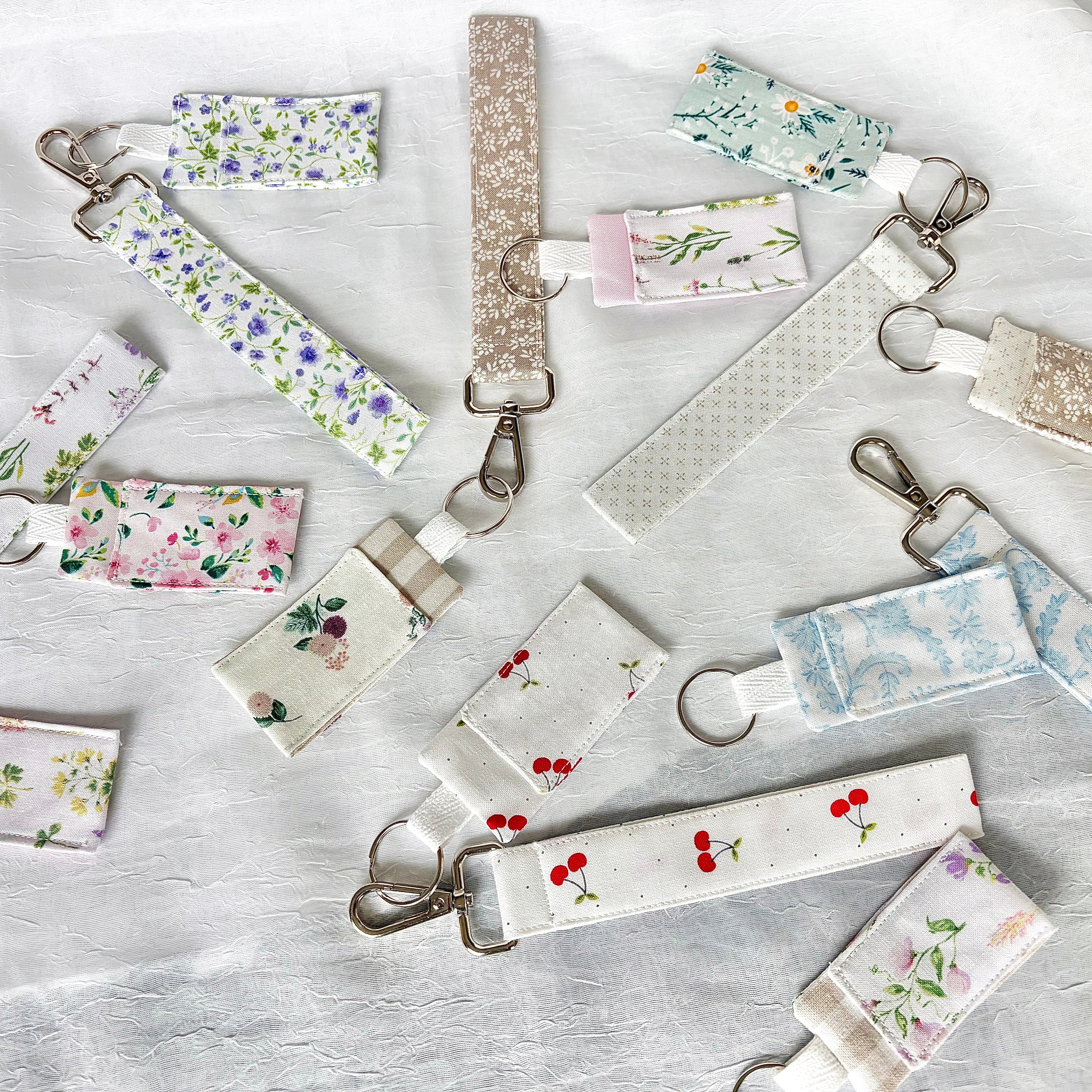 collection of keychain writlets and chapstick holders in various florals and printson a white background