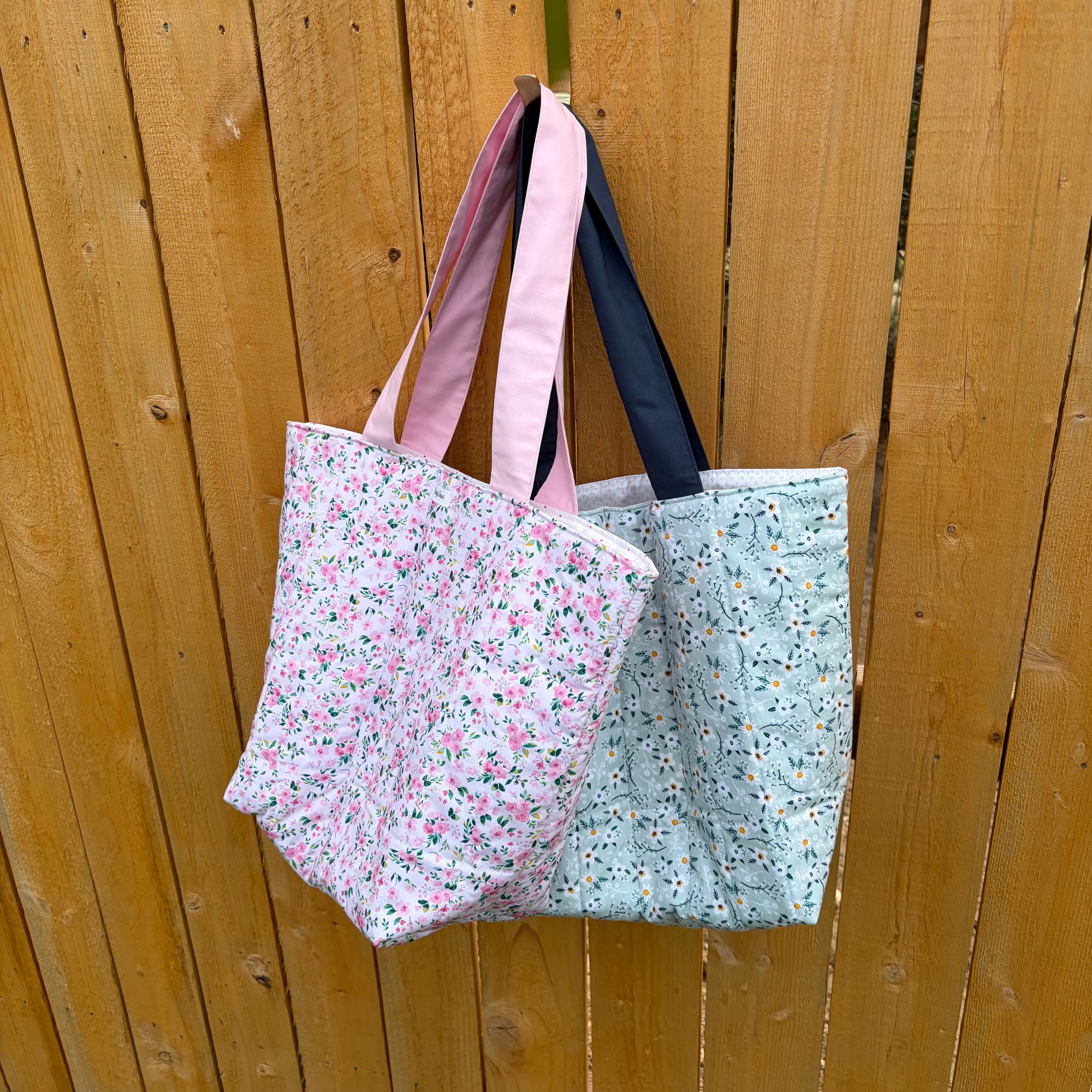pink floral and blue floral tote bags handing on a wooden fence