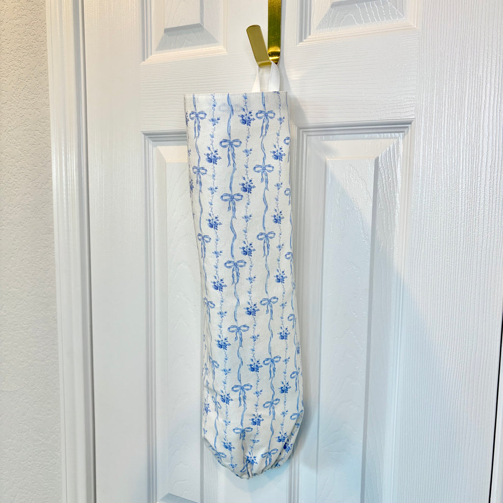 white Fabric Cylinder with bows in vertical pattern hanging on gold hook against white door