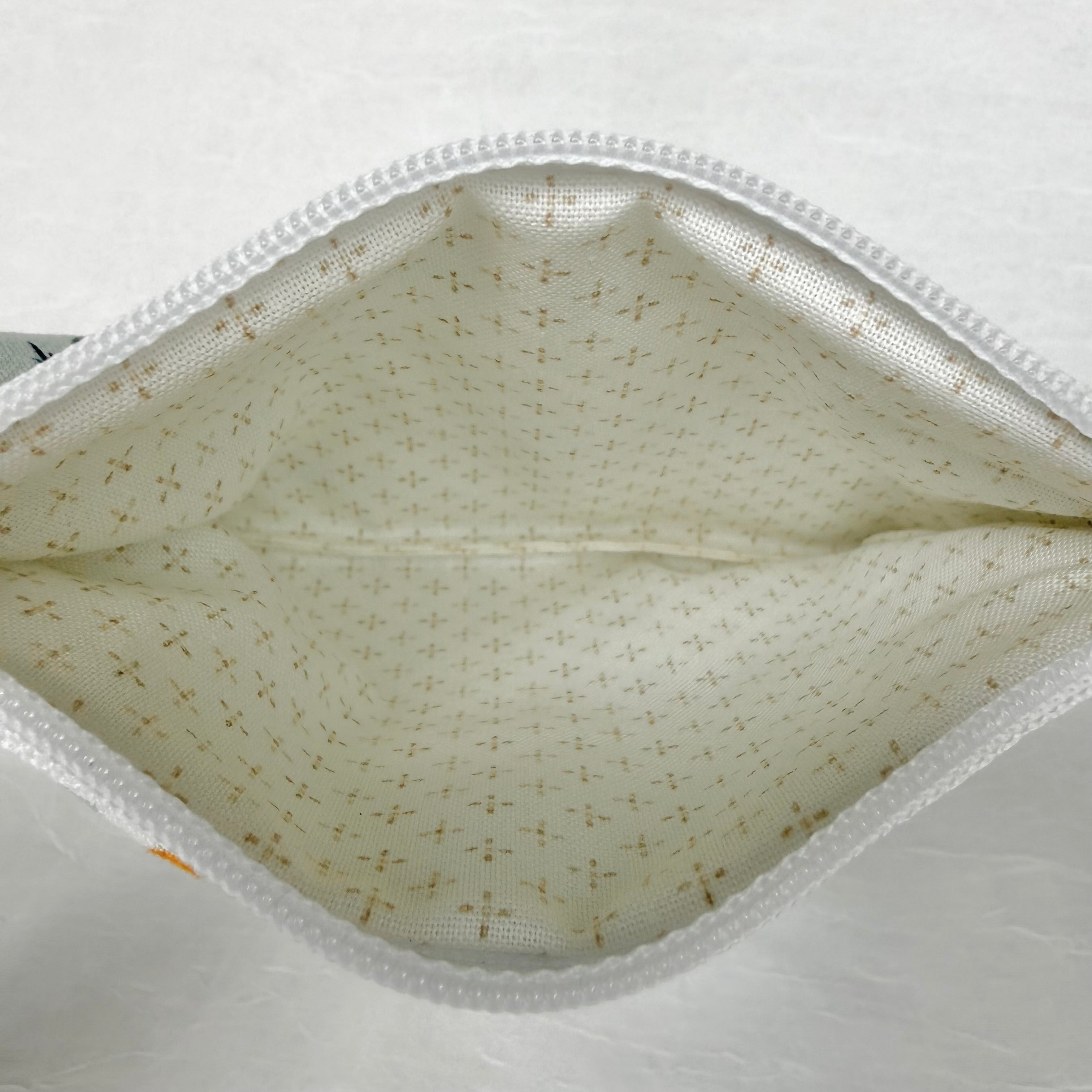Cream with brown dots in cross pattern interior with white zipper at top opening on white background