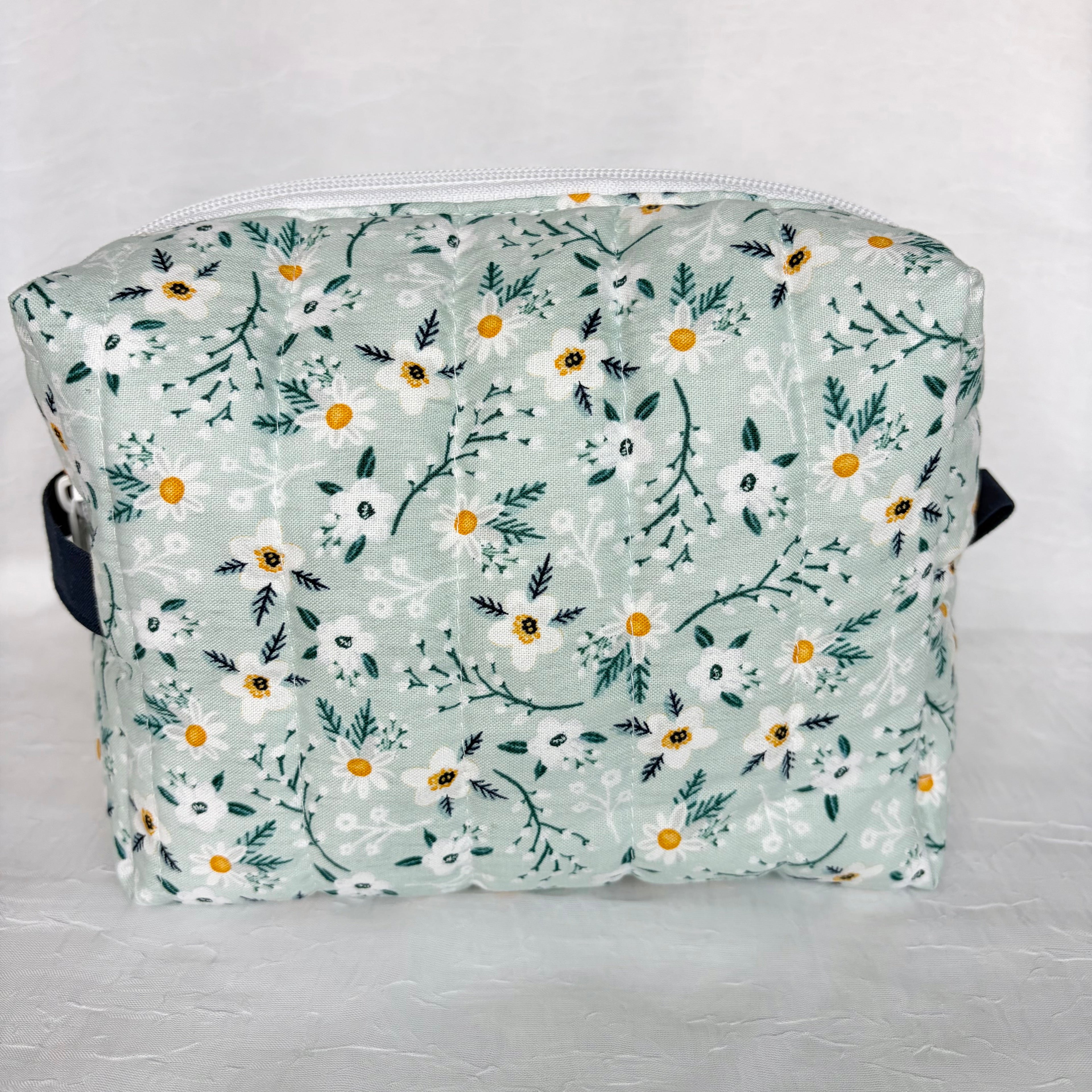 back view of blue with white flowers and teal leaf patterned boxy bag with navy accents on white background