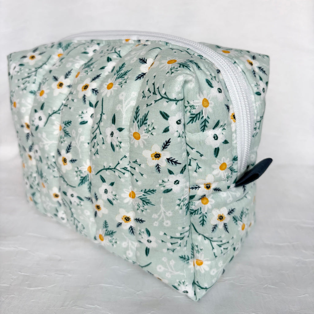 side view of navy pull tab and white zipper on blue with white flowers and teal leaf patterned boxy bag on white background