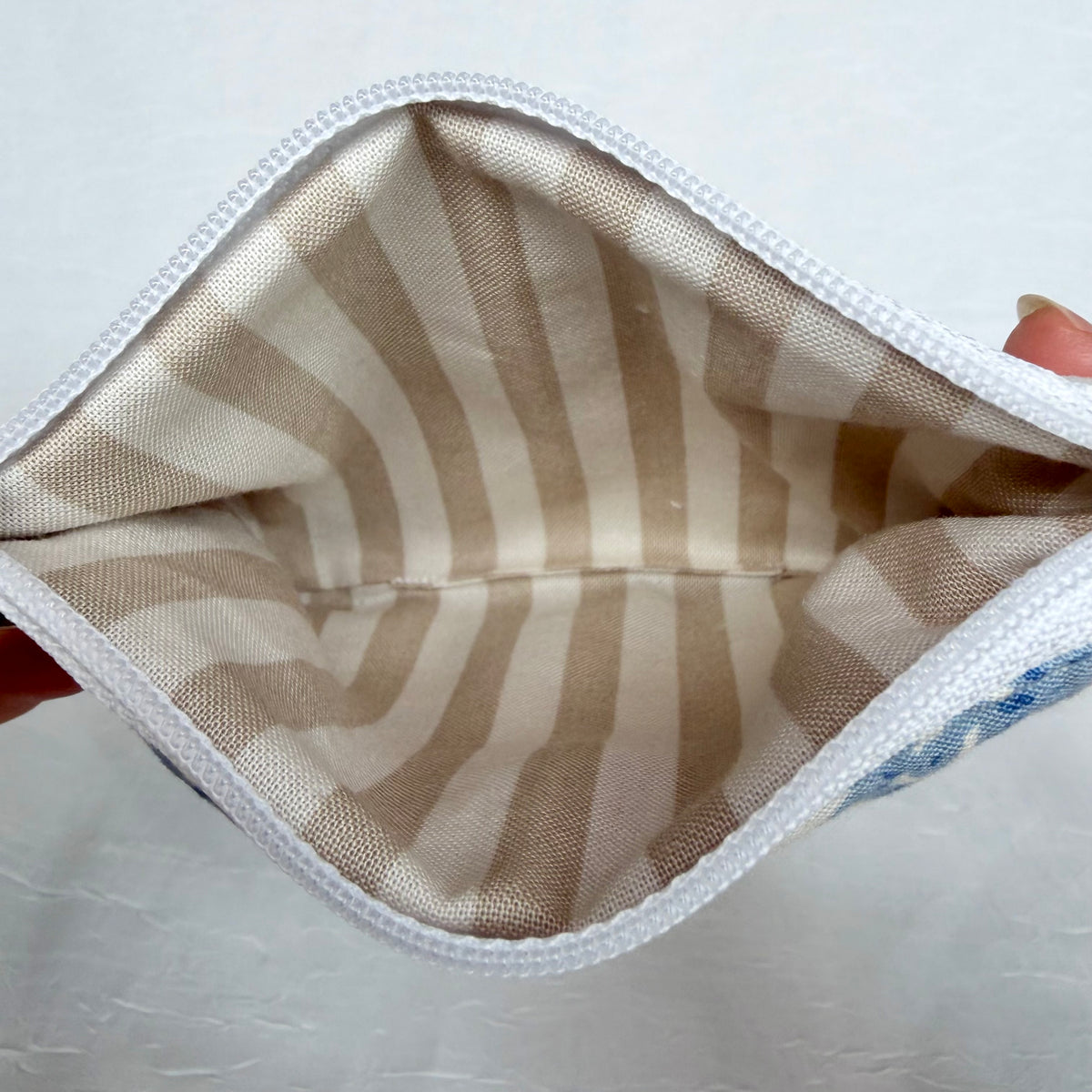 Tan and white striped interior with white zipper at top opening 