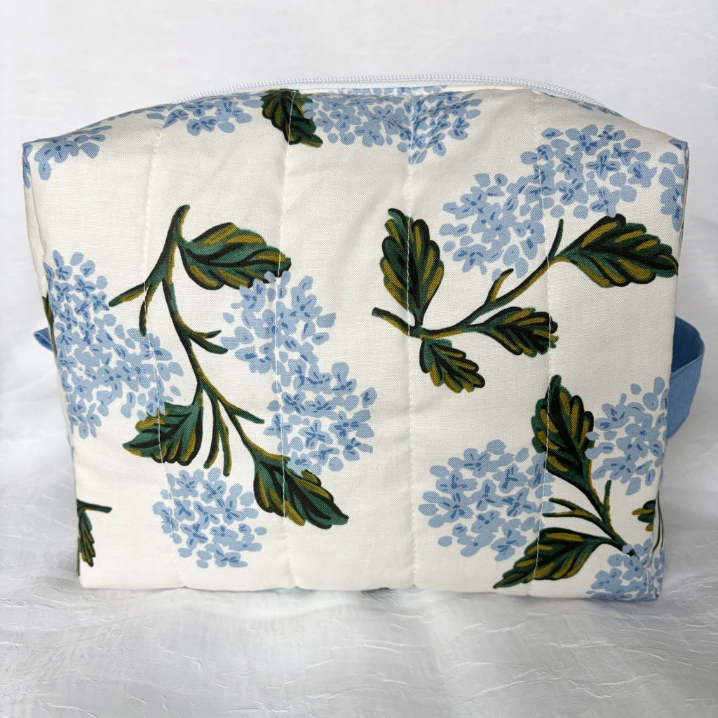 Back view of large blue hydrangea and green leaf designed boxy bag on white background