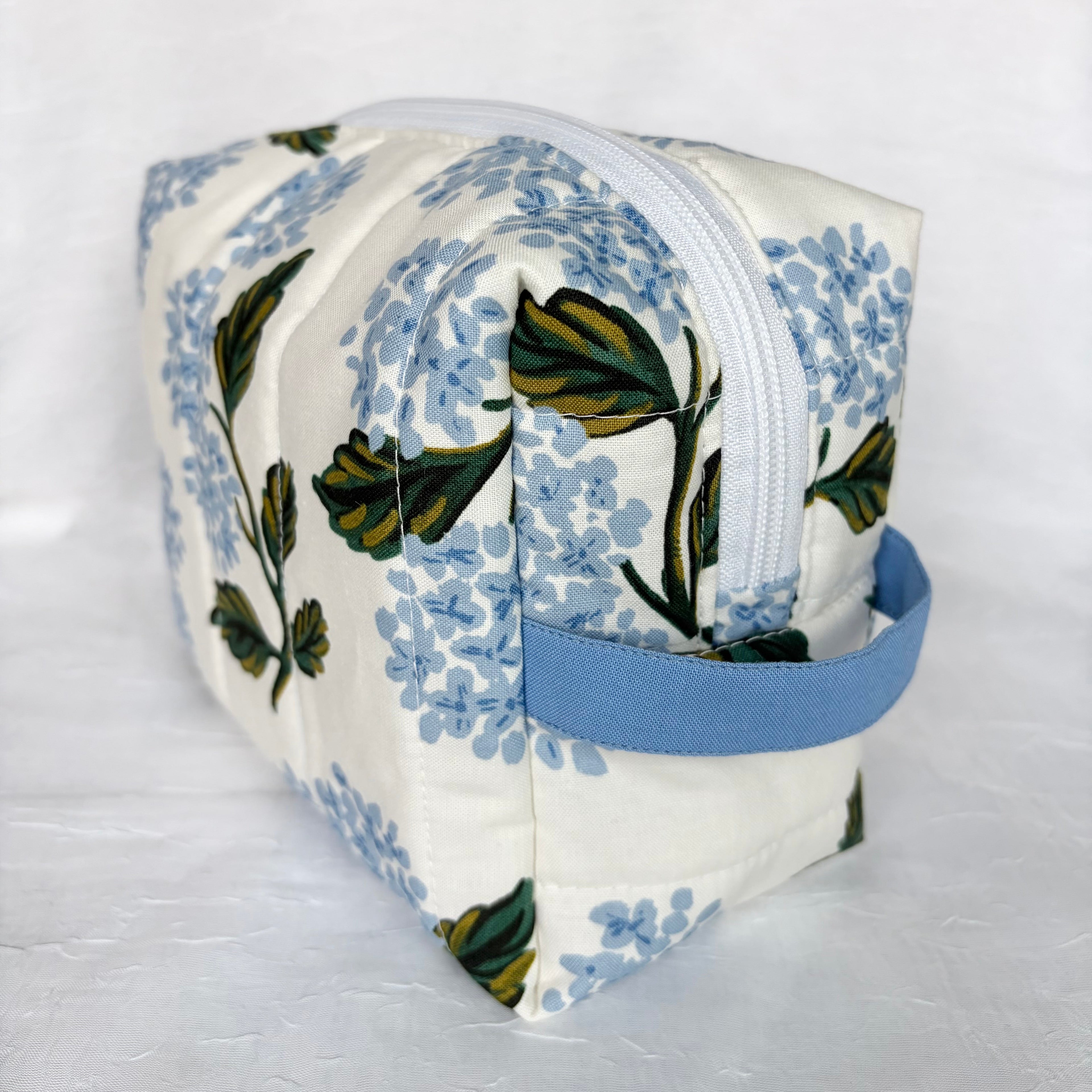 side view of blue handle and white zipper on large Blue Hydrangeas with green leaf design boxy bag on white background