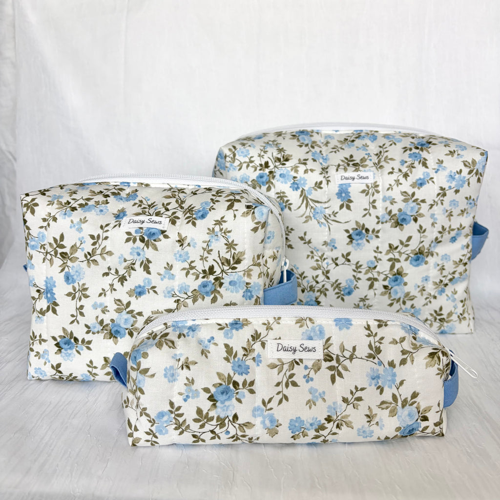 Three floral zippered cosmetic pouches in different sizes, featuring a blue and green floral pattern on a white background with a small 'Daisy Sews' label on each.