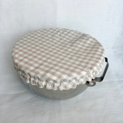 Beige gingham fabric cover on metal bowl on white background