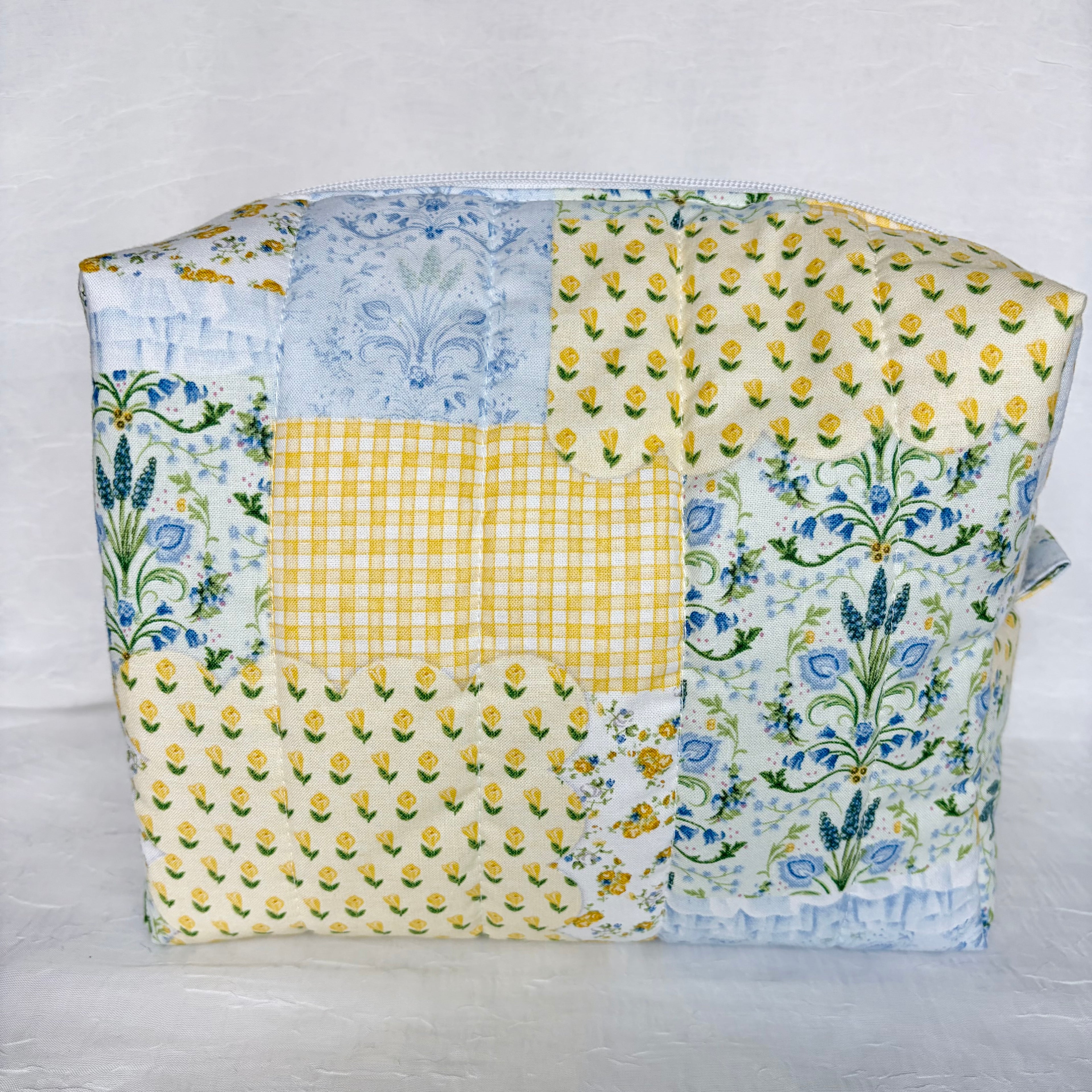 back view of blue and yellow floral patchwork boxy bag against white background