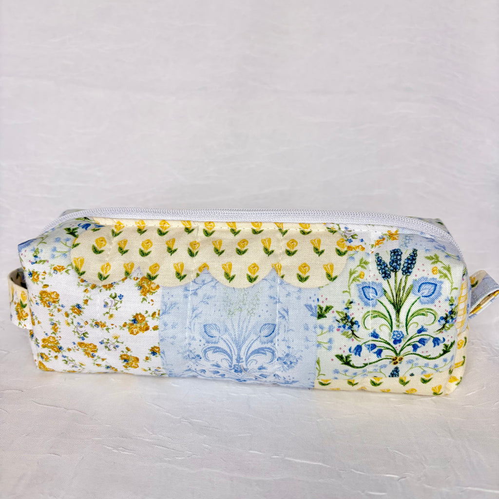 back view of blue and yellow floral patchwork boxy bag against white background