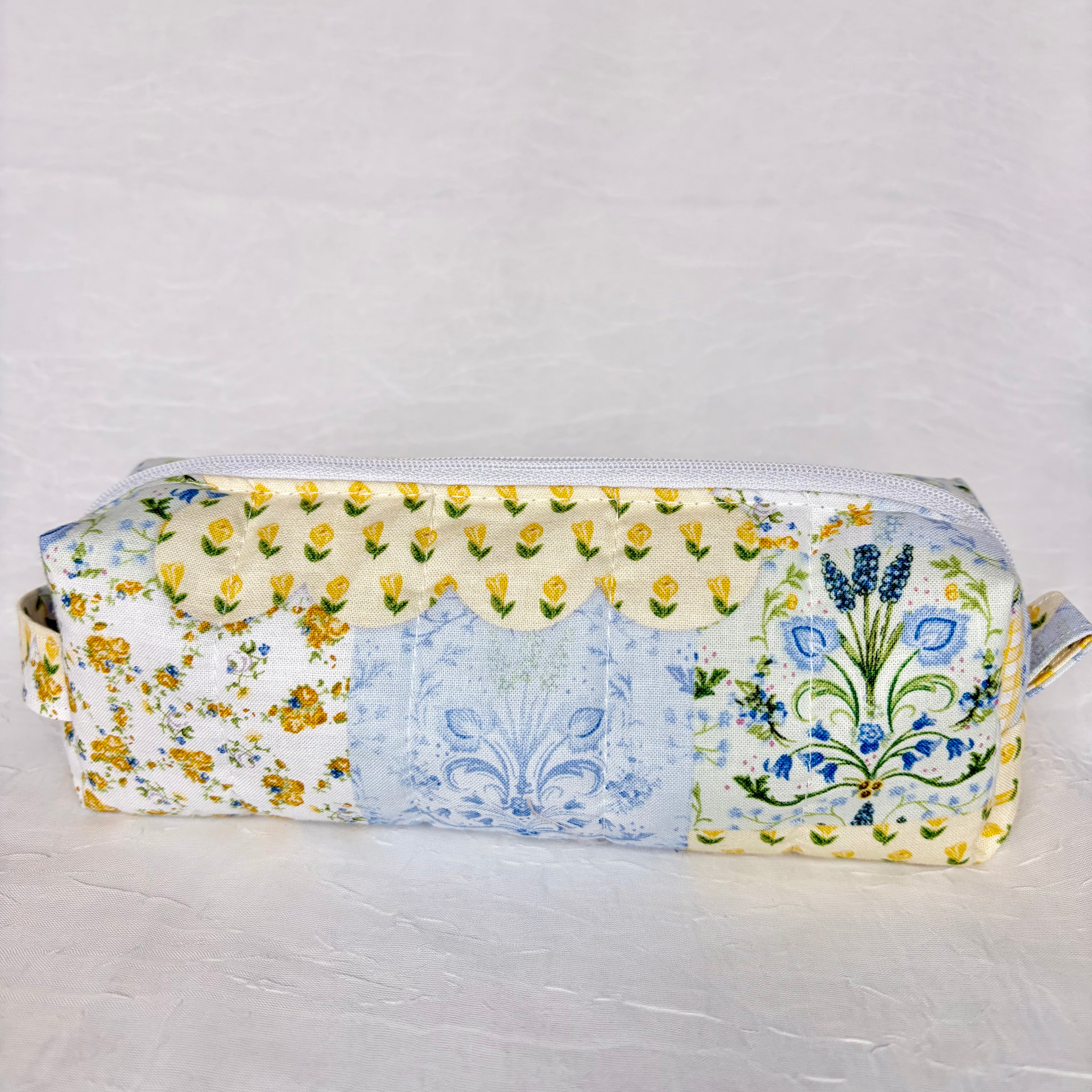 back view of blue and yellow floral patchwork boxy bag against white background