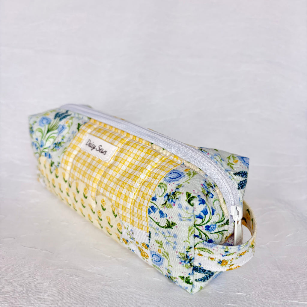 side view of handle on blue and yellow floral patchwork boxy bag against white background