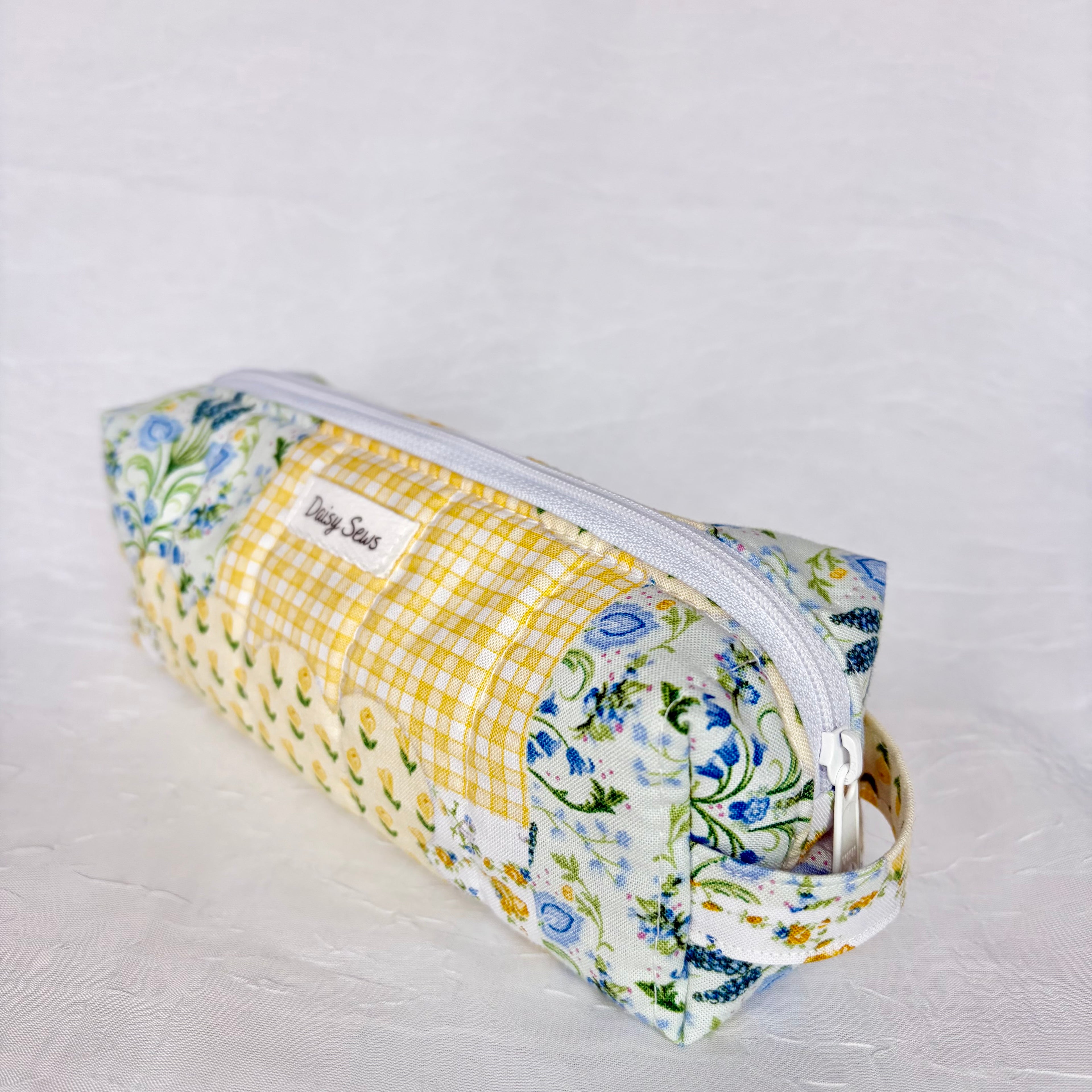 side view of handle on blue and yellow floral patchwork boxy bag against white background