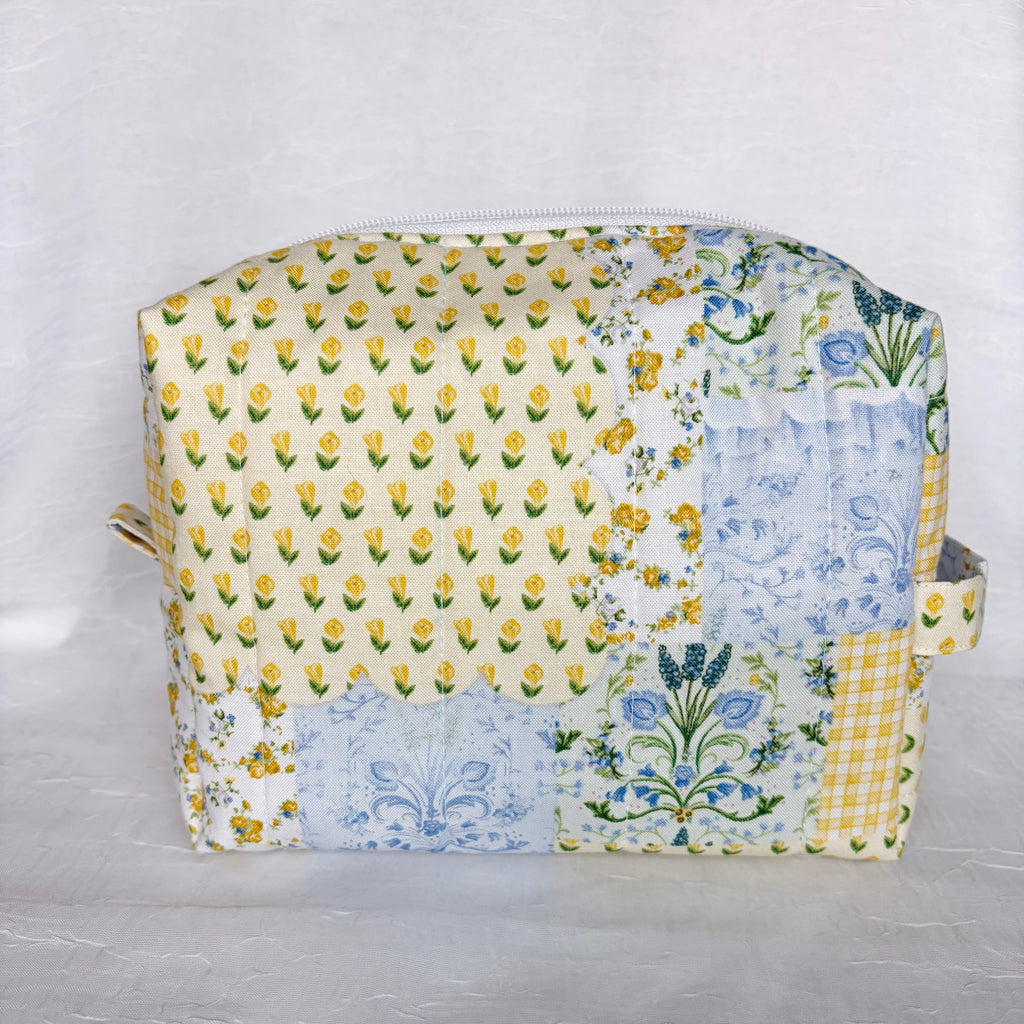Blue and Yellow floral Patchwork boxy bag with handle , pull tab and whit zipper against white background