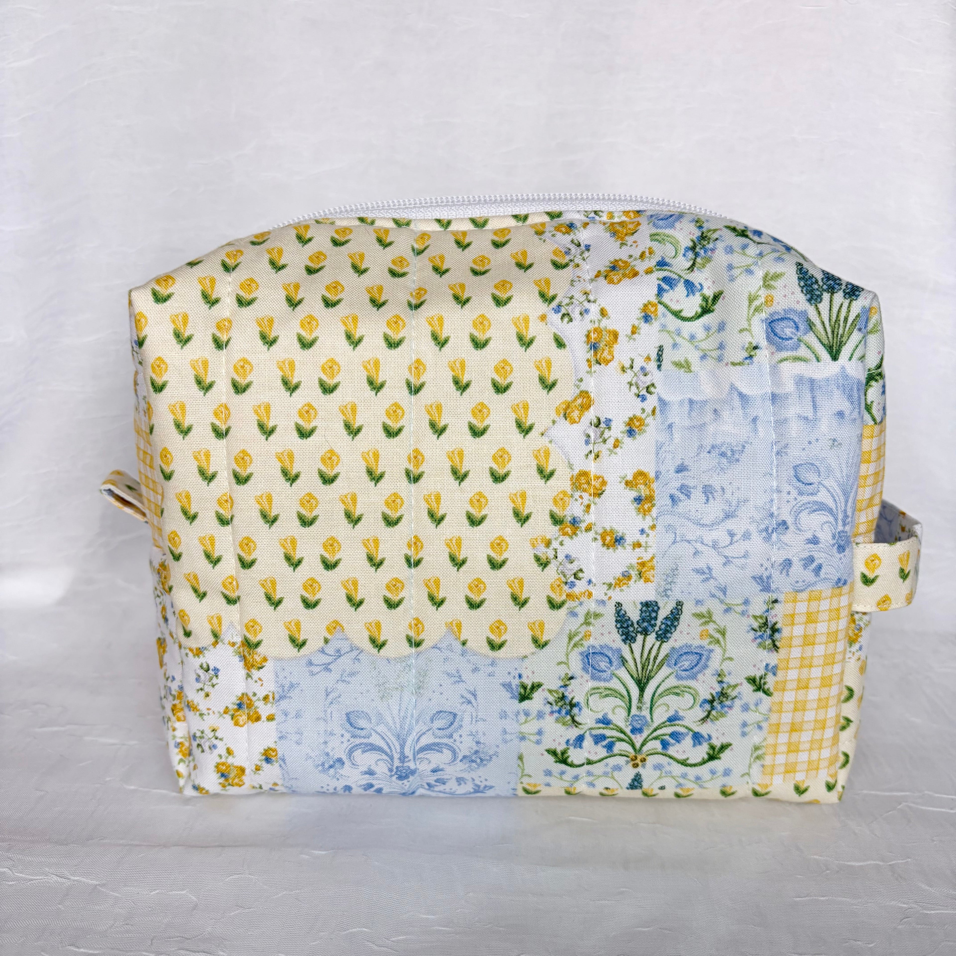 Blue and Yellow floral Patchwork boxy bag with handle , pull tab and whit zipper against white background
