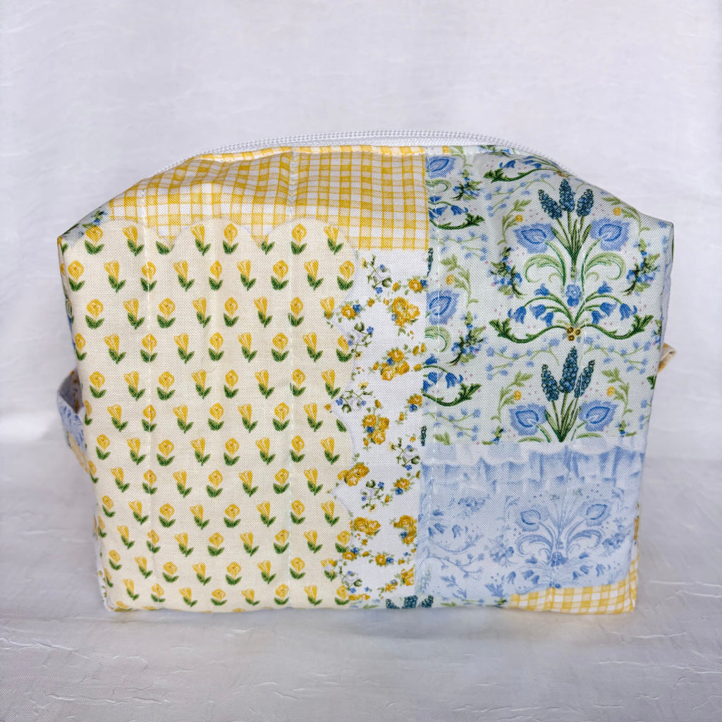 Back View of Blue and Yellow floral Patchwork boxy bag with white zipper against white background