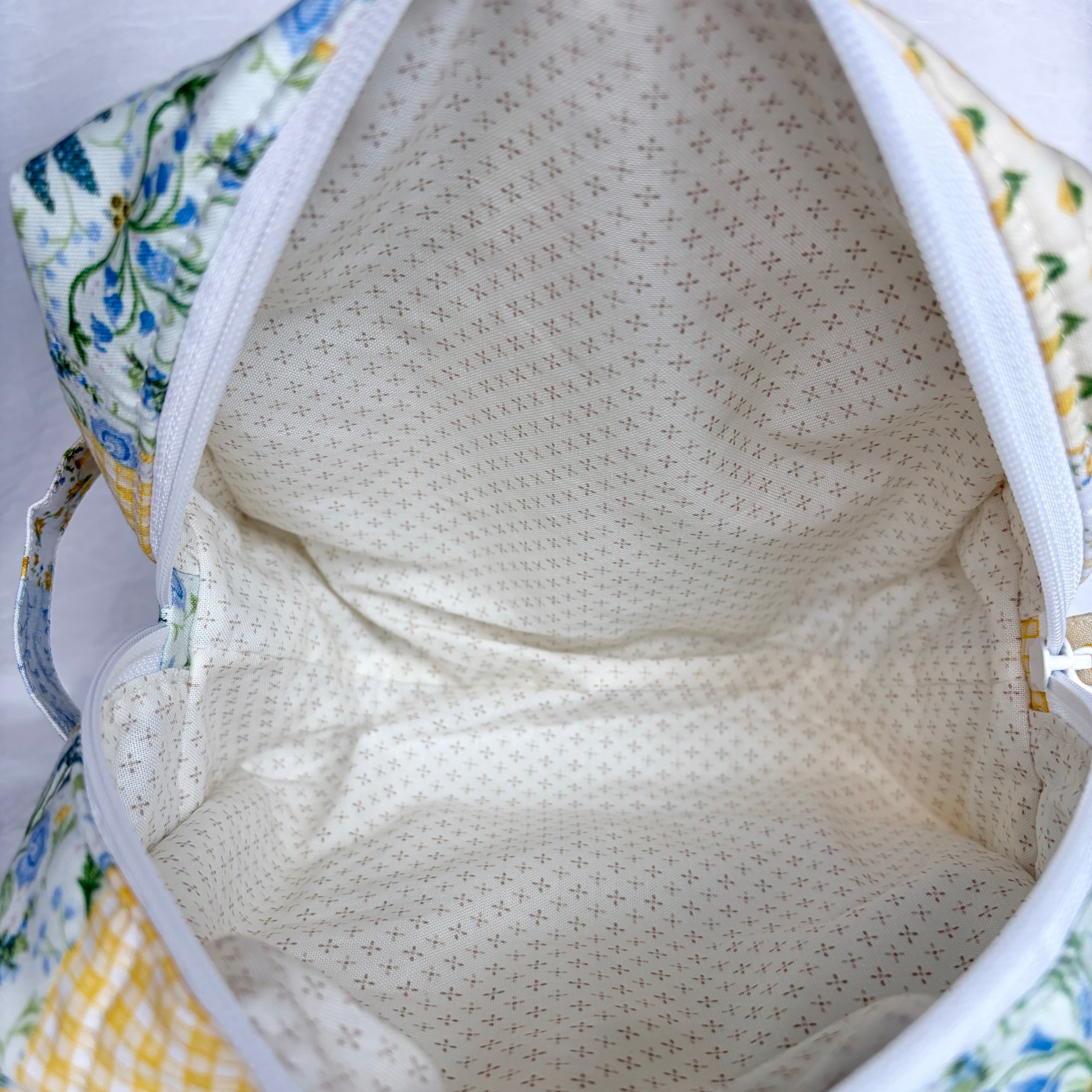 Close up of cream with brown dots in cross pattern interior with white zipper at opening