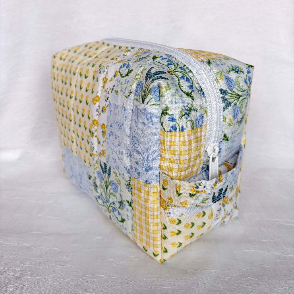 side view of handle on Blue and Yellow floral Patchwork boxy bag with white zipper against white background