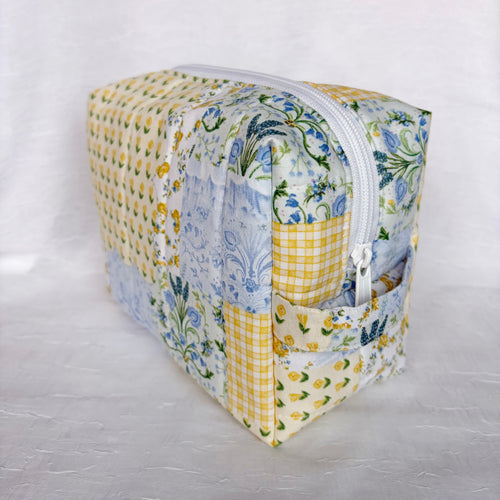 side view of handle on Blue and Yellow floral Patchwork boxy bag with white zipper against white background