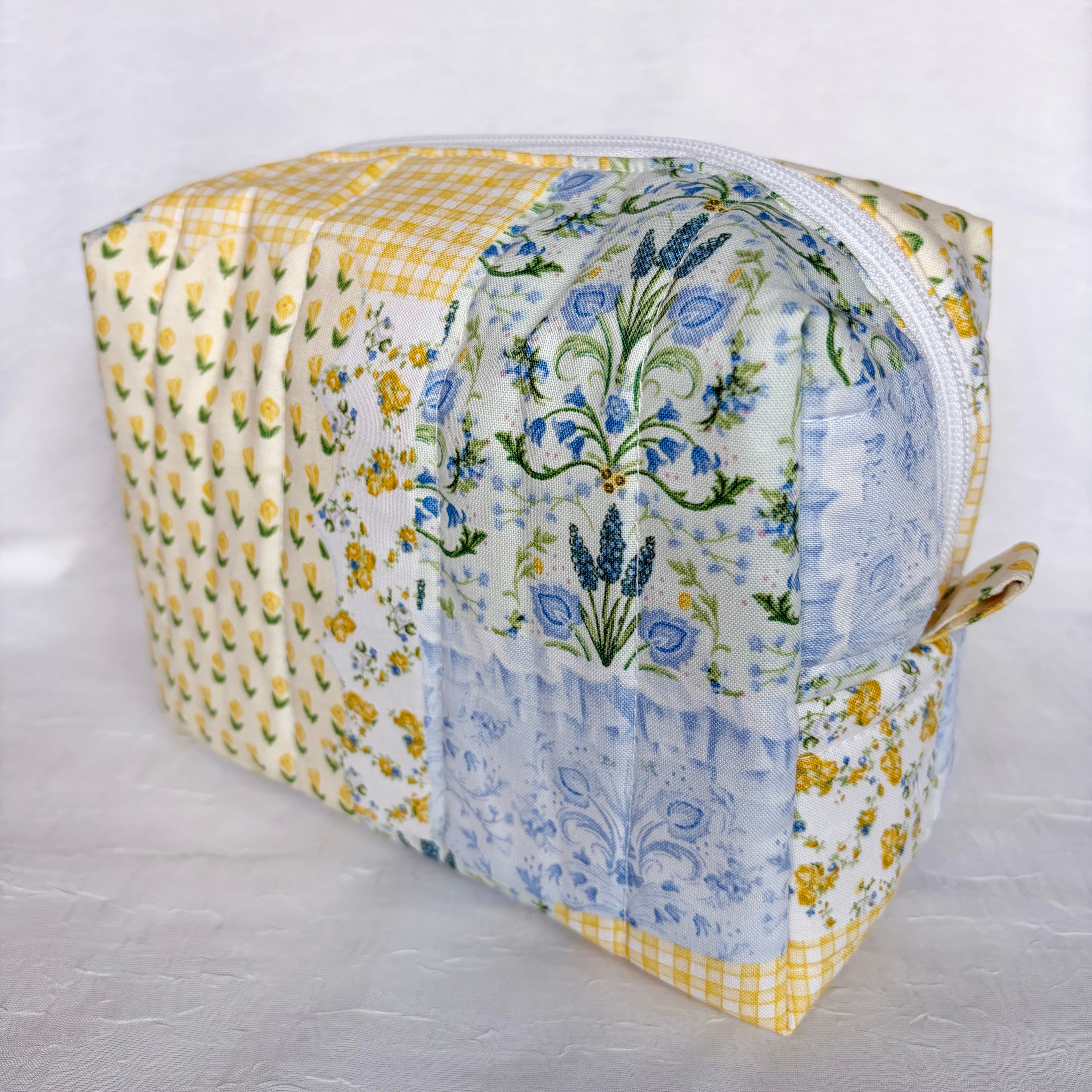 side view of pull tab on Blue and Yellow floral Patchwork boxy bag with white zipper against white background