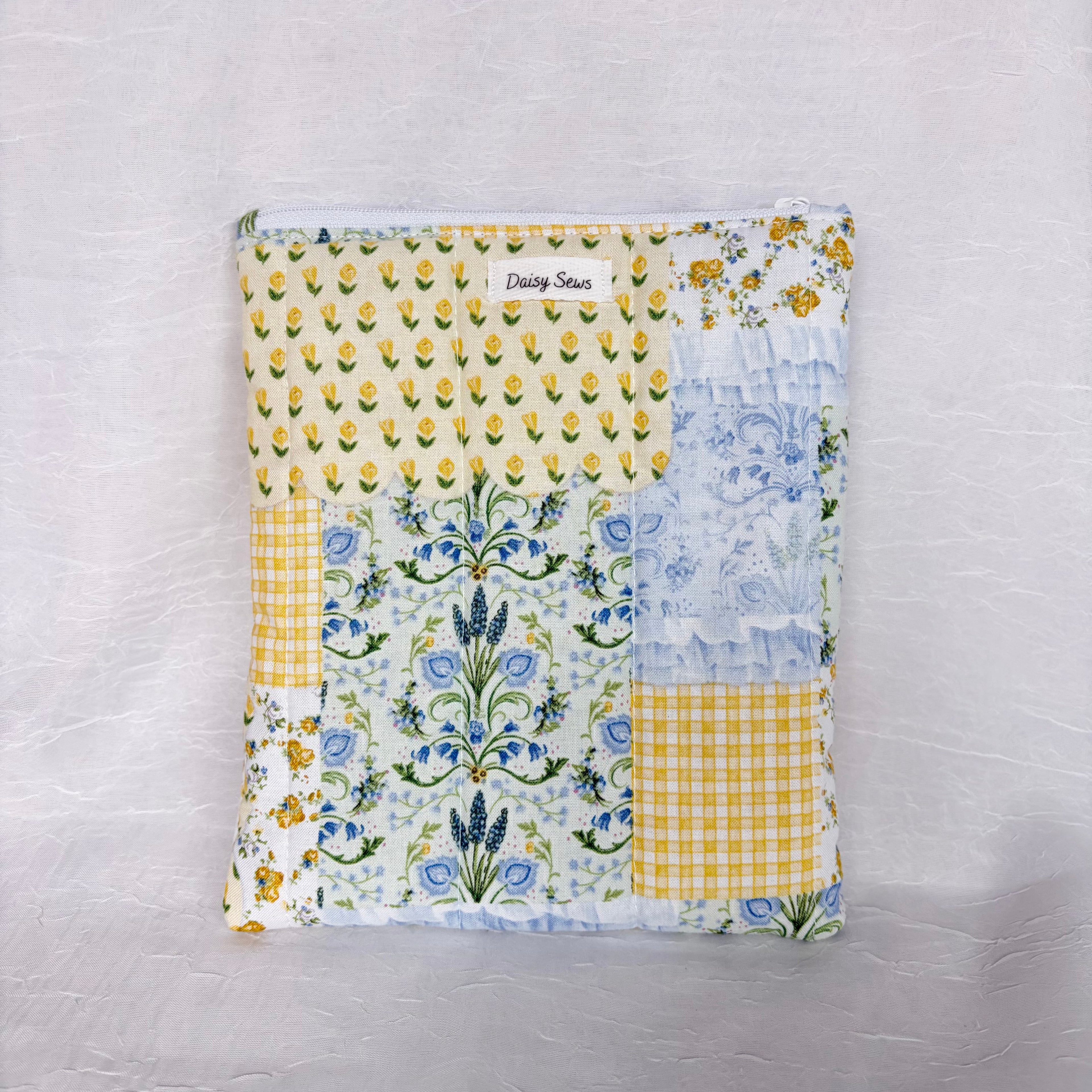 Blue and Yellow floral Patchwork fabric, plush, flat pouch with white zipper on white background