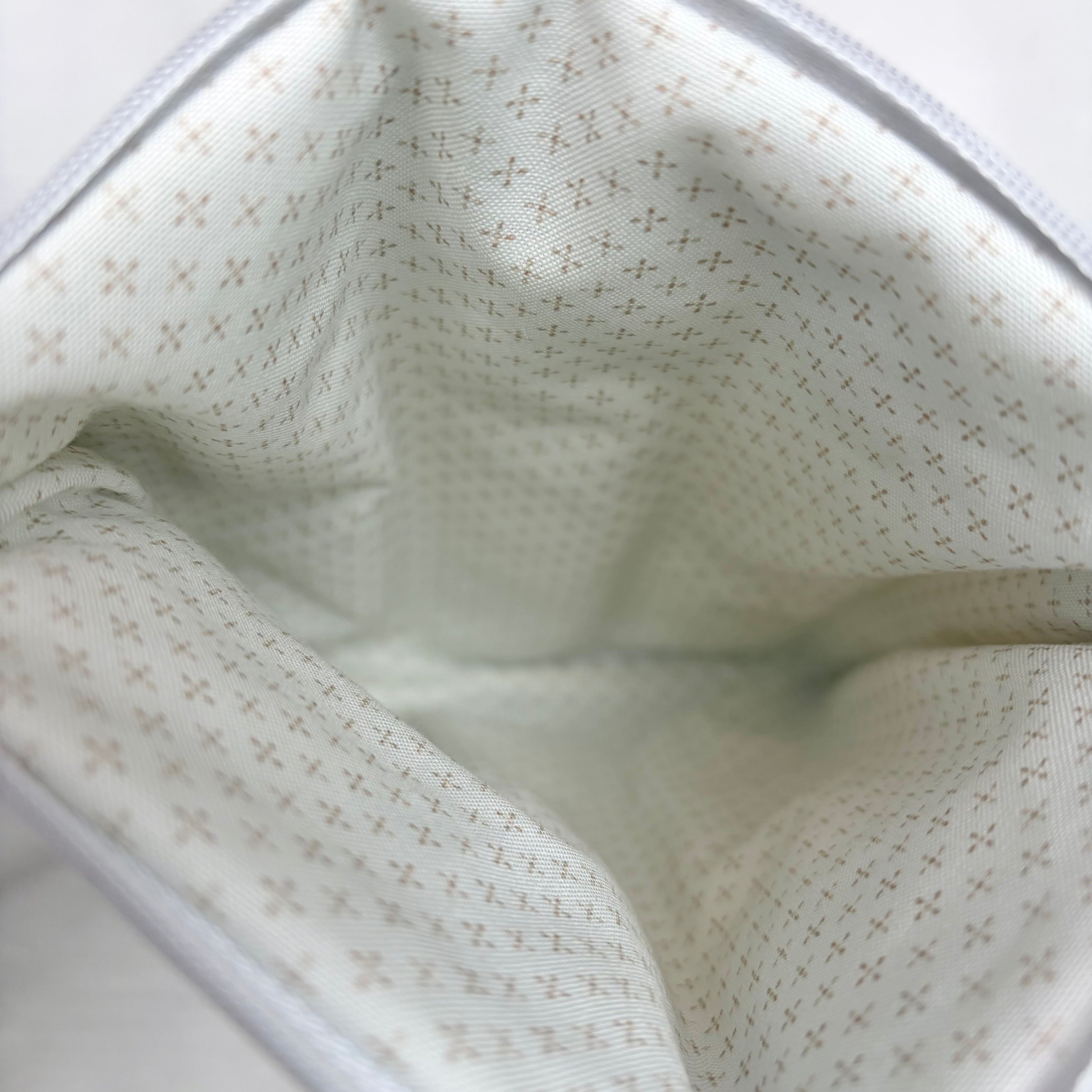close up of cream interior with brown dots in cross pattern and white zipper and top opening