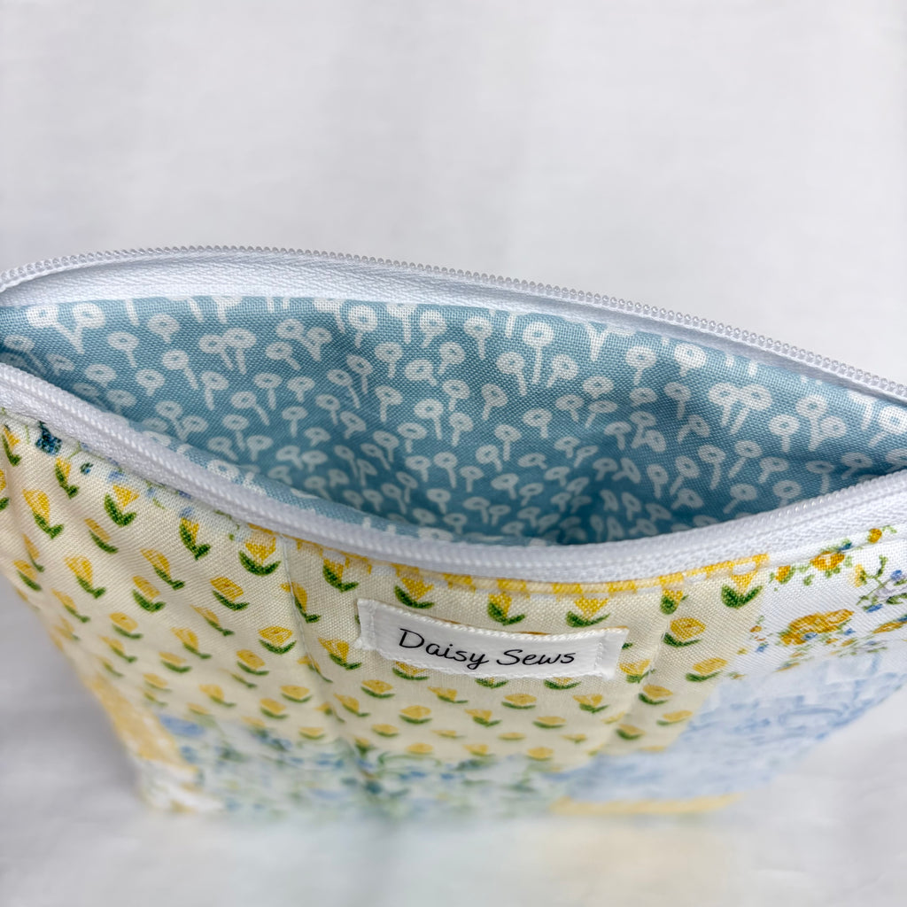 yellow and blue floral exterior with blue interior with white flower design and white zipper at top opening on white background