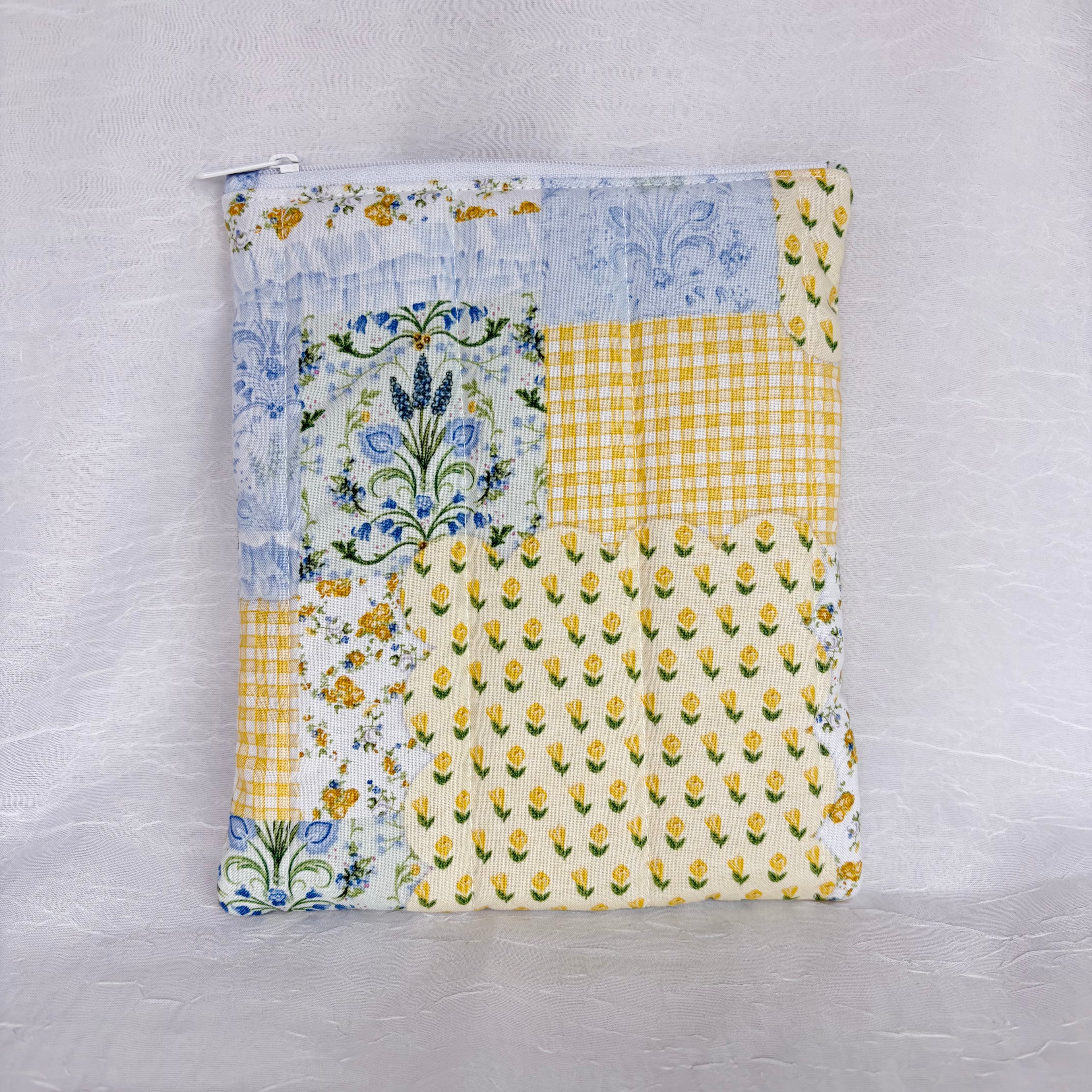 back of Blue and Yellow floral Patchwork fabric, plush, flat pouch with white zipper on white background