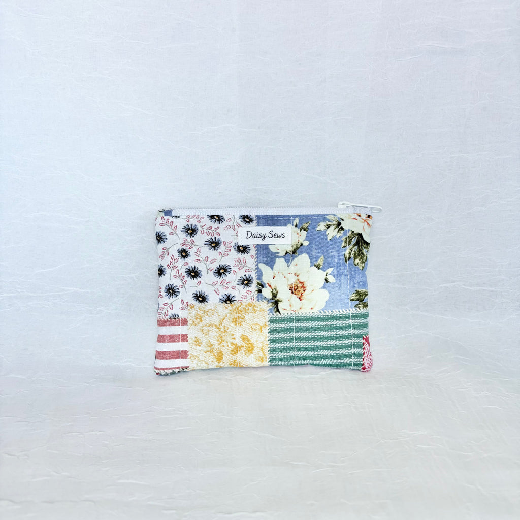 Patchwork pouch with floral and striped patterns on a light blue background
