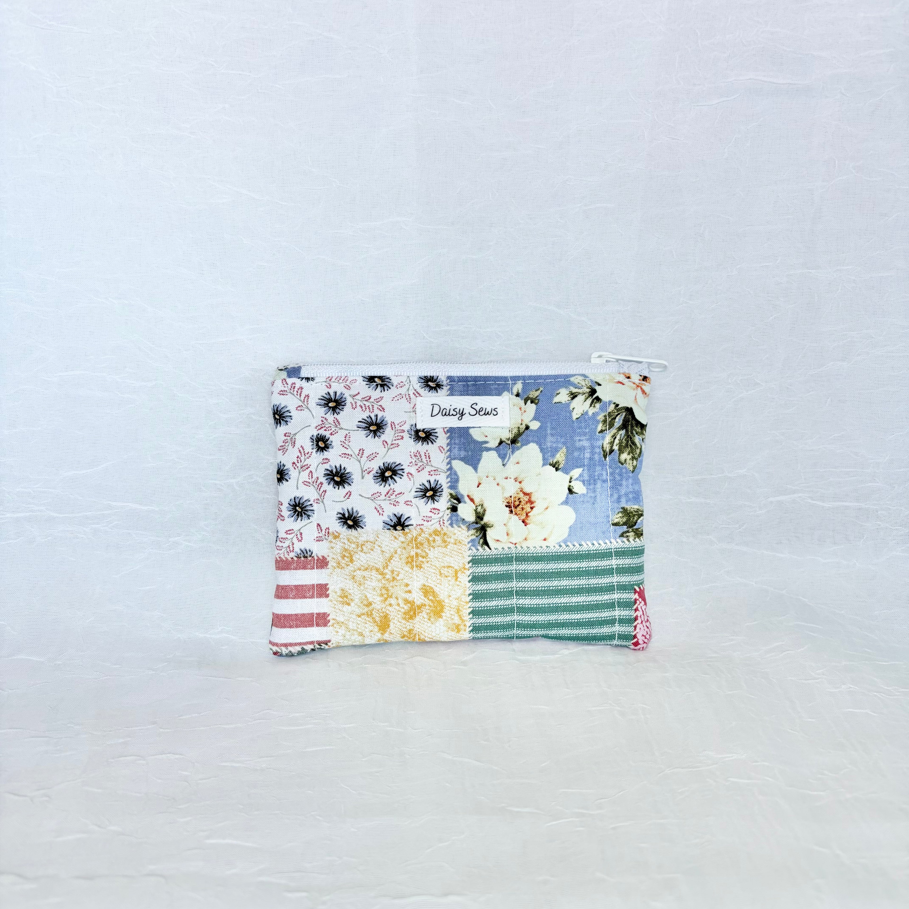 Patchwork pouch with floral and striped patterns on a light blue background