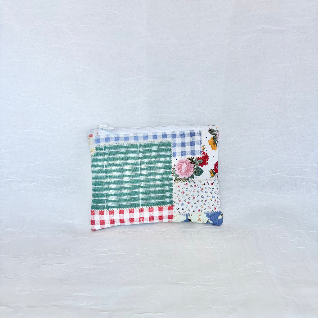 Patchwork pouch with floral, striped, and checkered patterns on a light gray background
