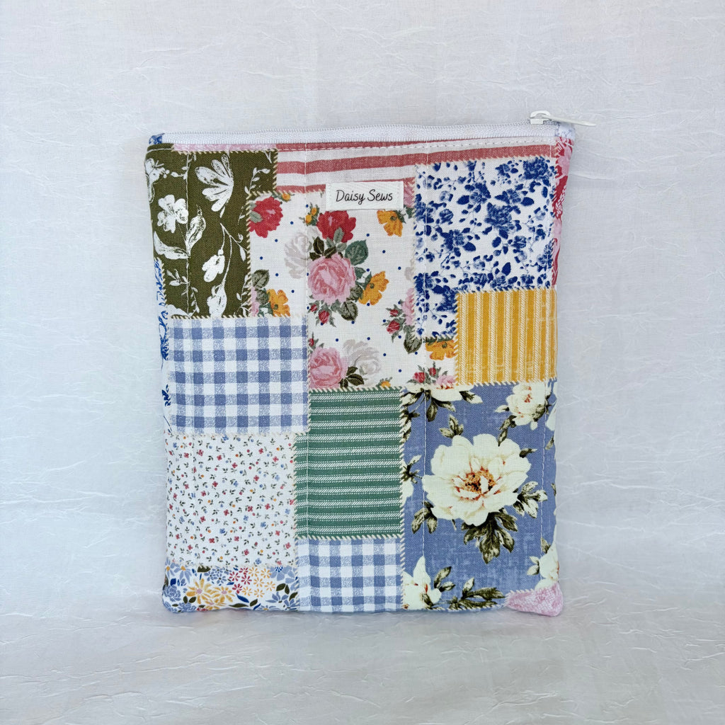 Patchwork-style pouch with floral and plaid patterns on a light background