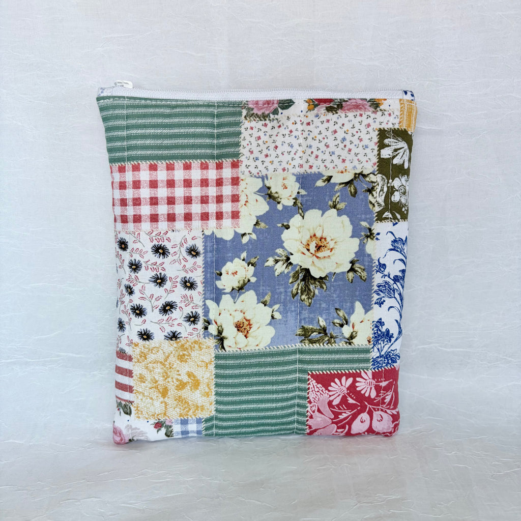 Patchwork-style pouch with floral and plaid patterns on a light gray background