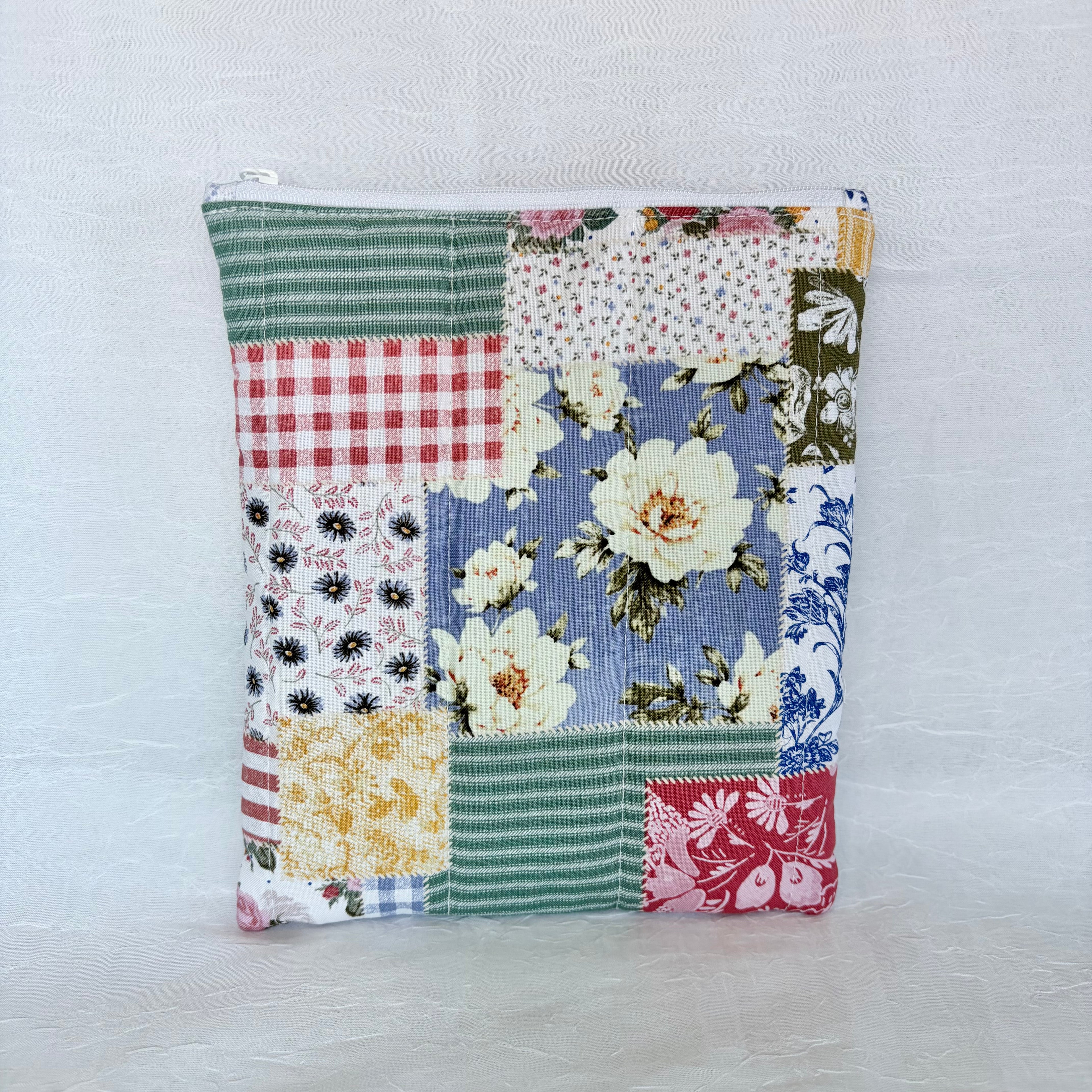 Patchwork-style pouch with floral and plaid patterns on a light gray background