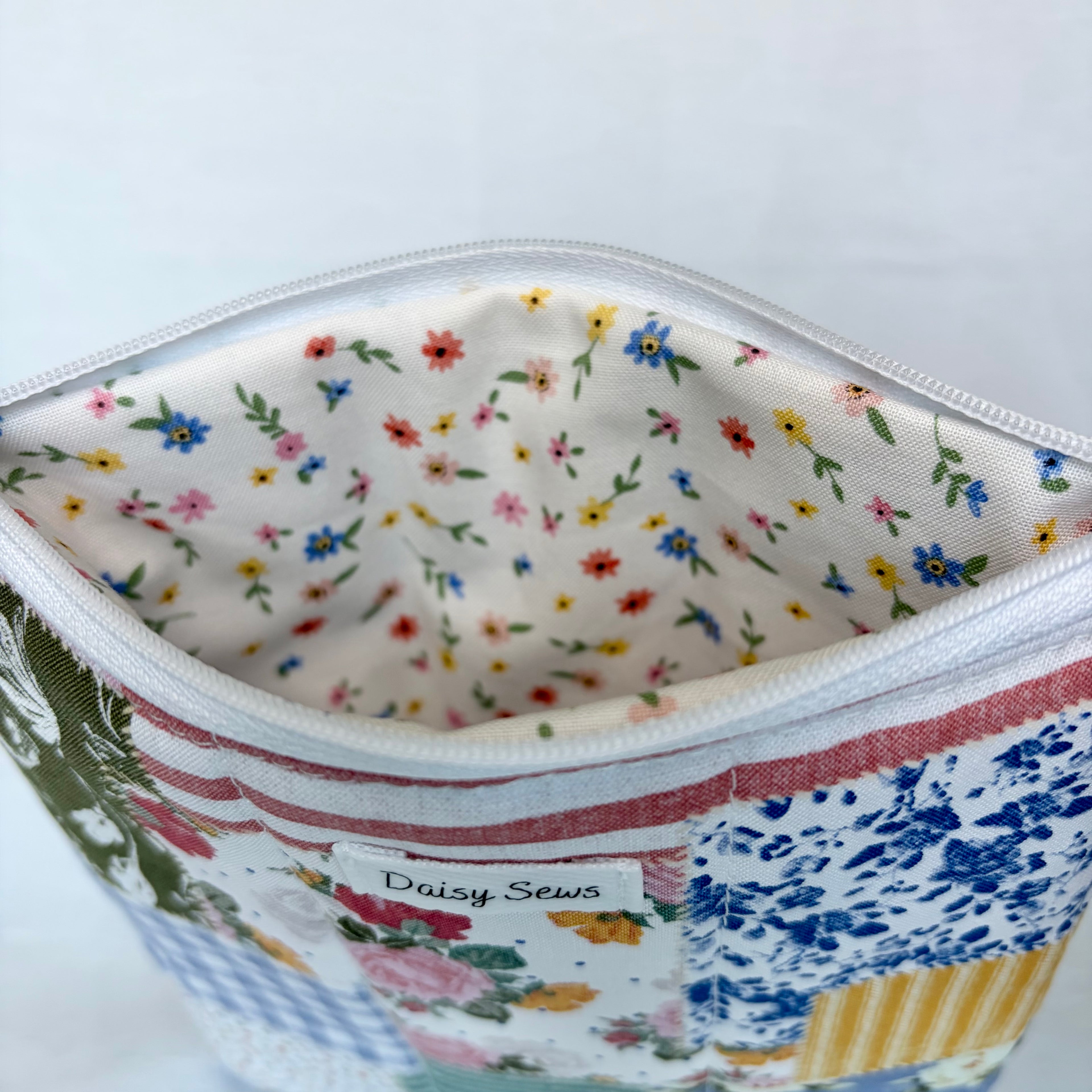 Fabric pouch with floral lining and 'Daisy Sews' label on a white background