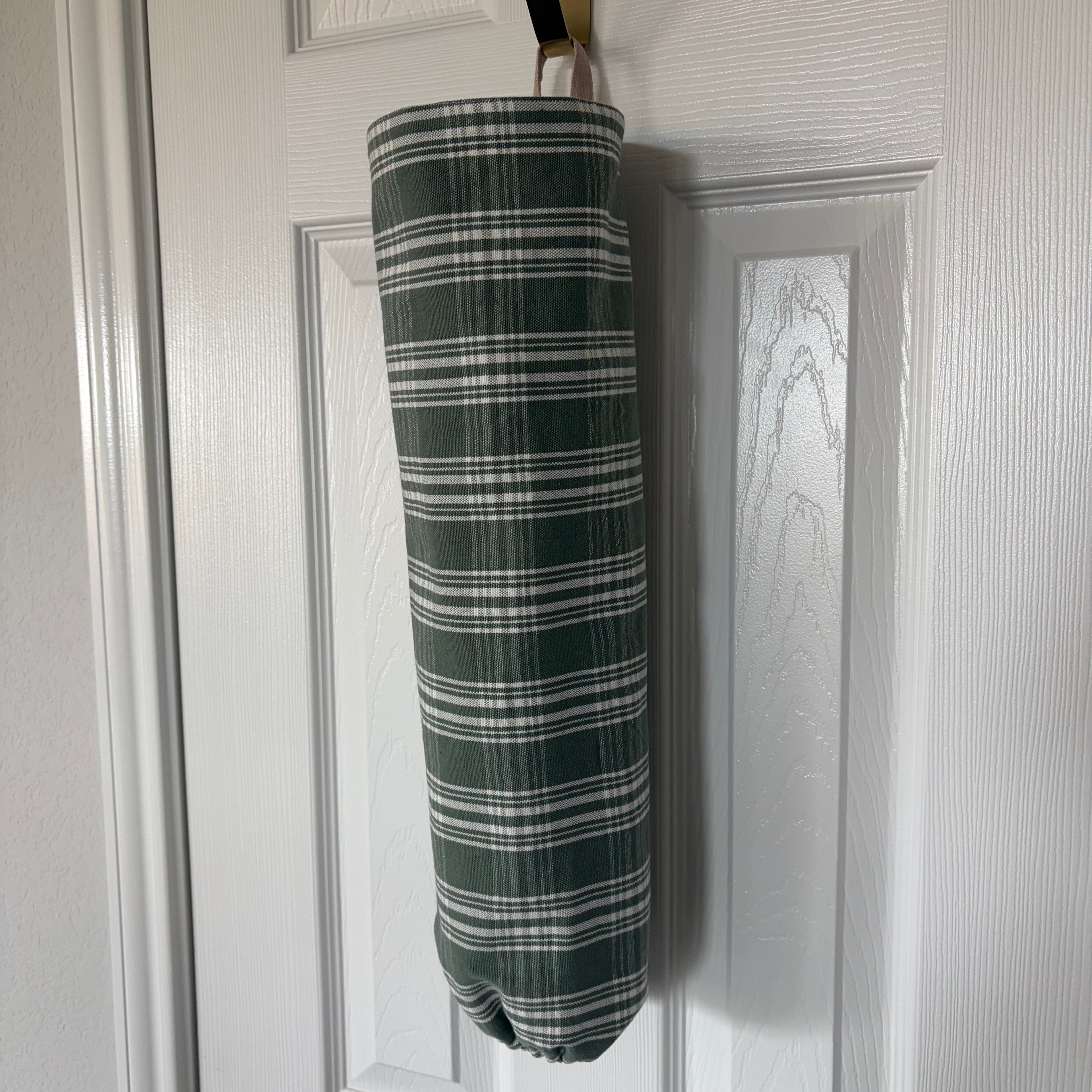 Green and White Plaid fabric in cylindrical shape with tan hook at the top and elastic on the bottom