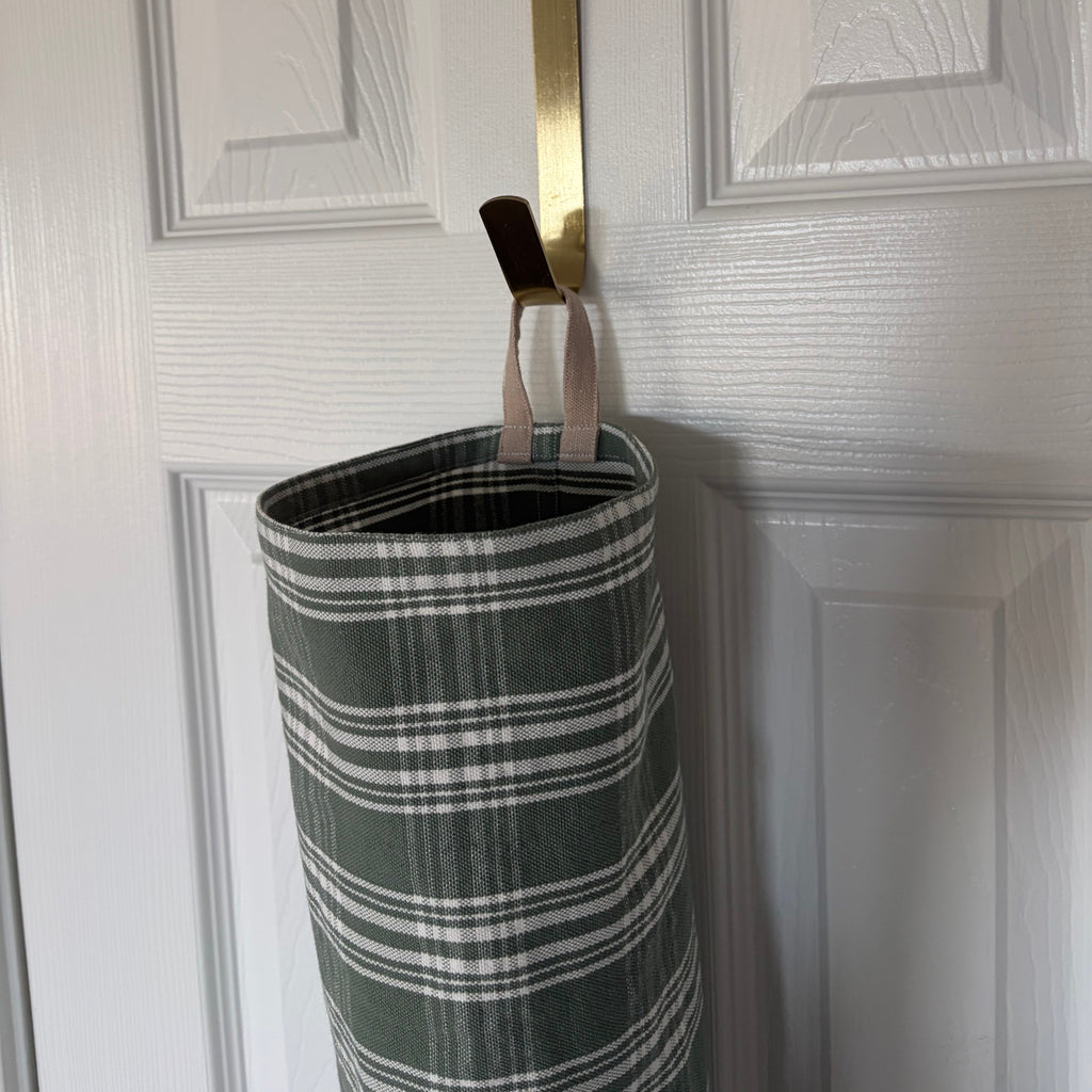  top view of hook holding the bag over a door. fabric in cylindrical shape with tan hook at the top and elastic on the bottom