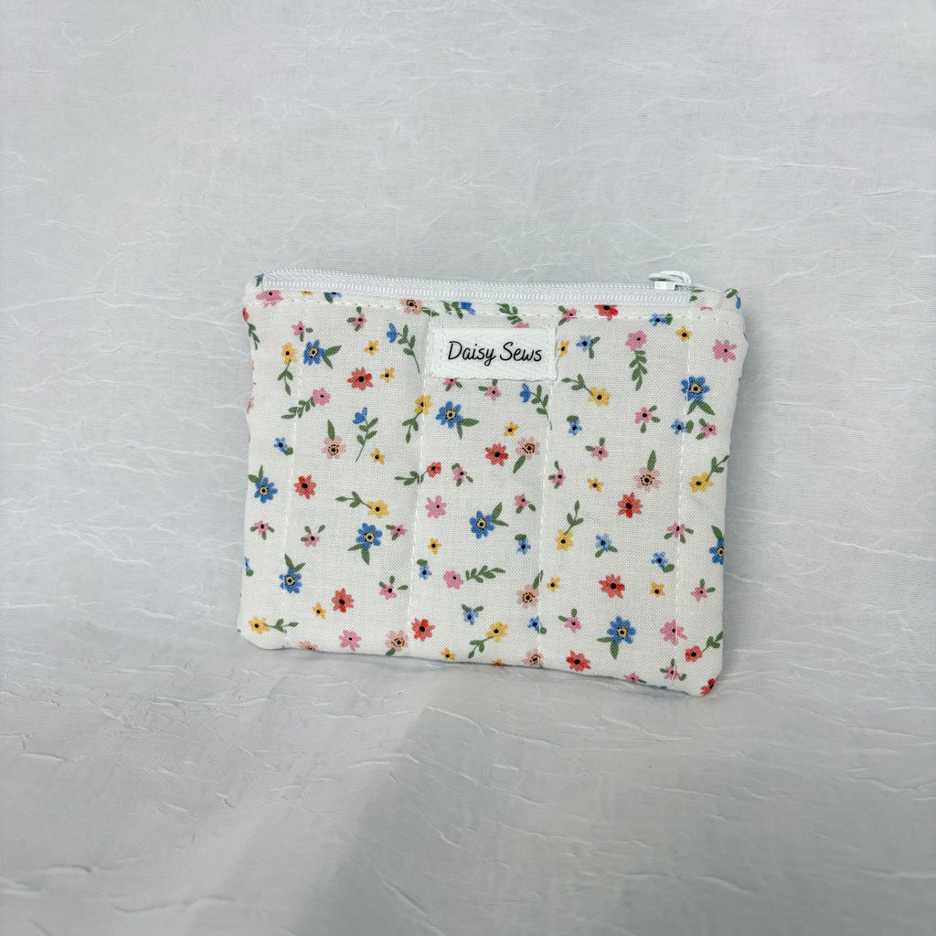 Blue, Yellow, Pink, and red flower design on small white pouch with white zipper on white background