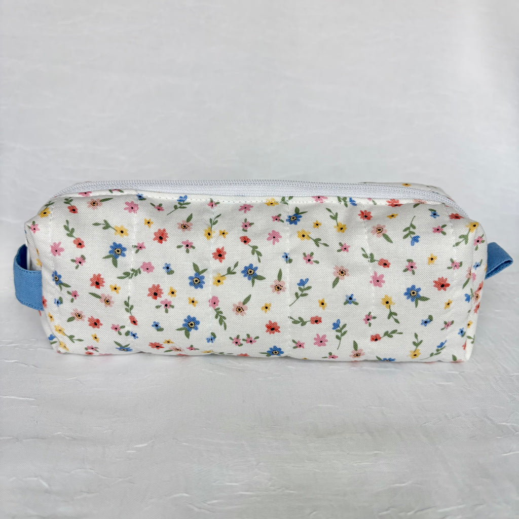 Back view of mini blue, yellow, pink and red floral-patterned pencil case with blue accents on a white background