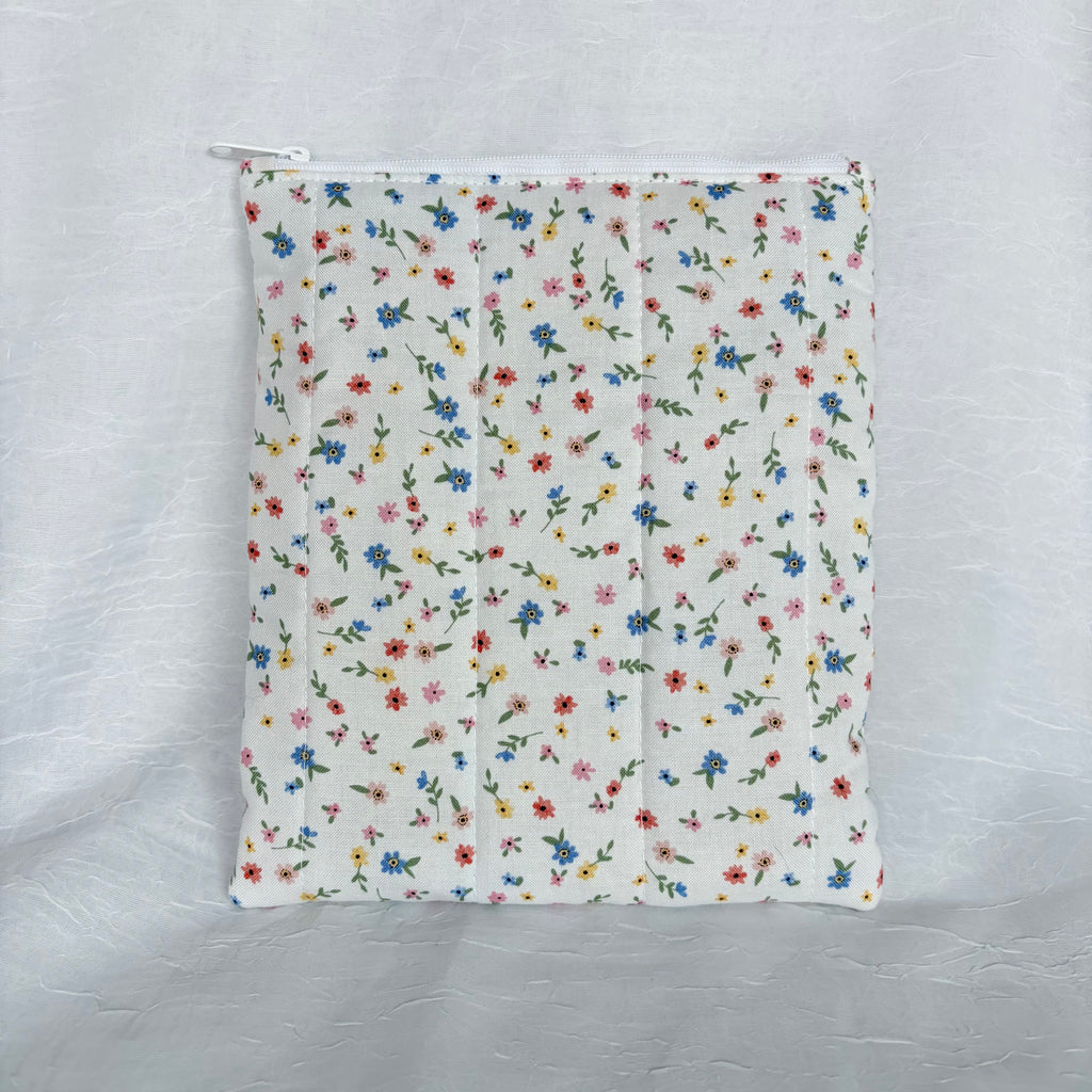 back of small blue, yellow, pink and red flowers with green leaf design on white fabric, plush flat pouch with white zipper on white background
