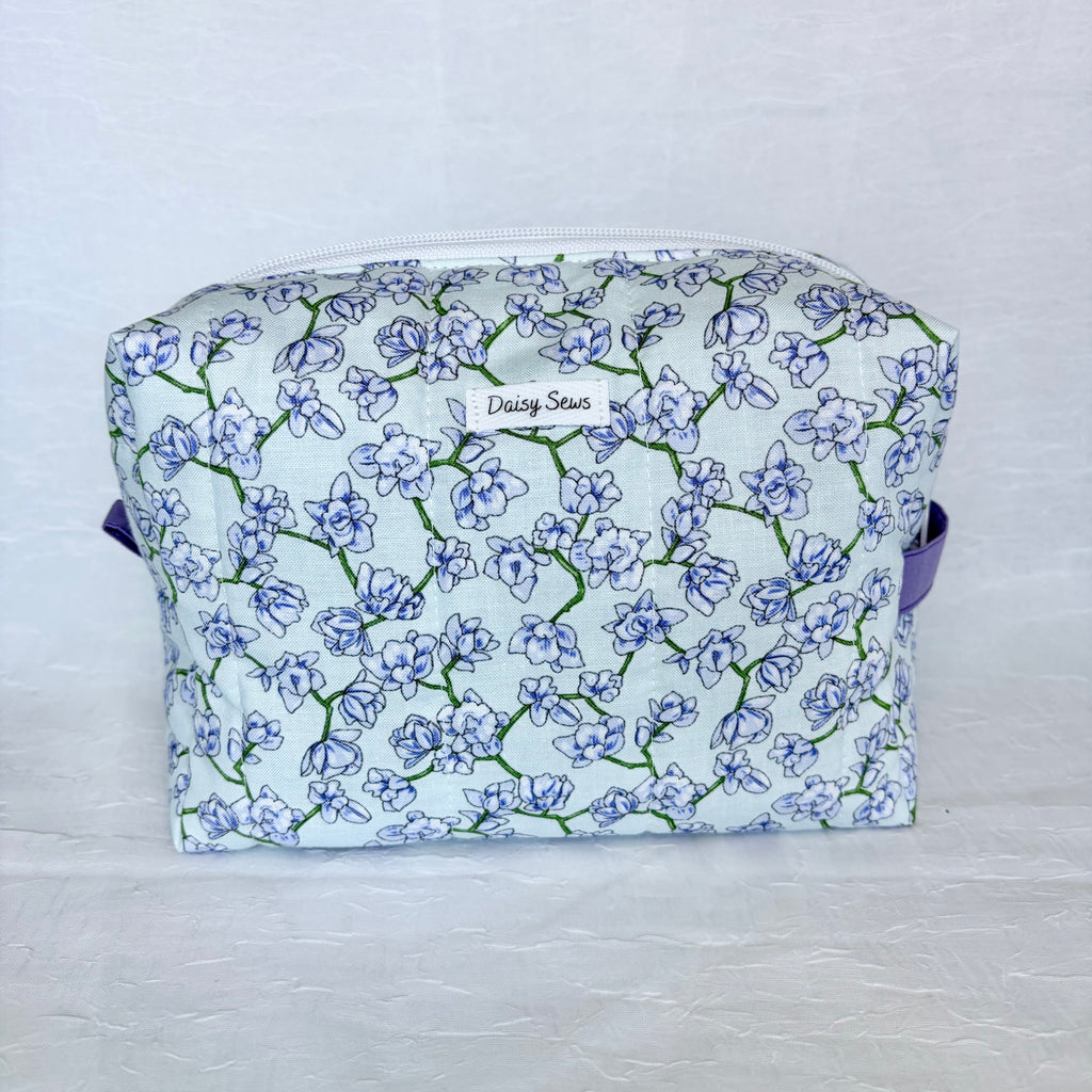 light blue Floral-patterned fabric bag with a visible brand name on a light background