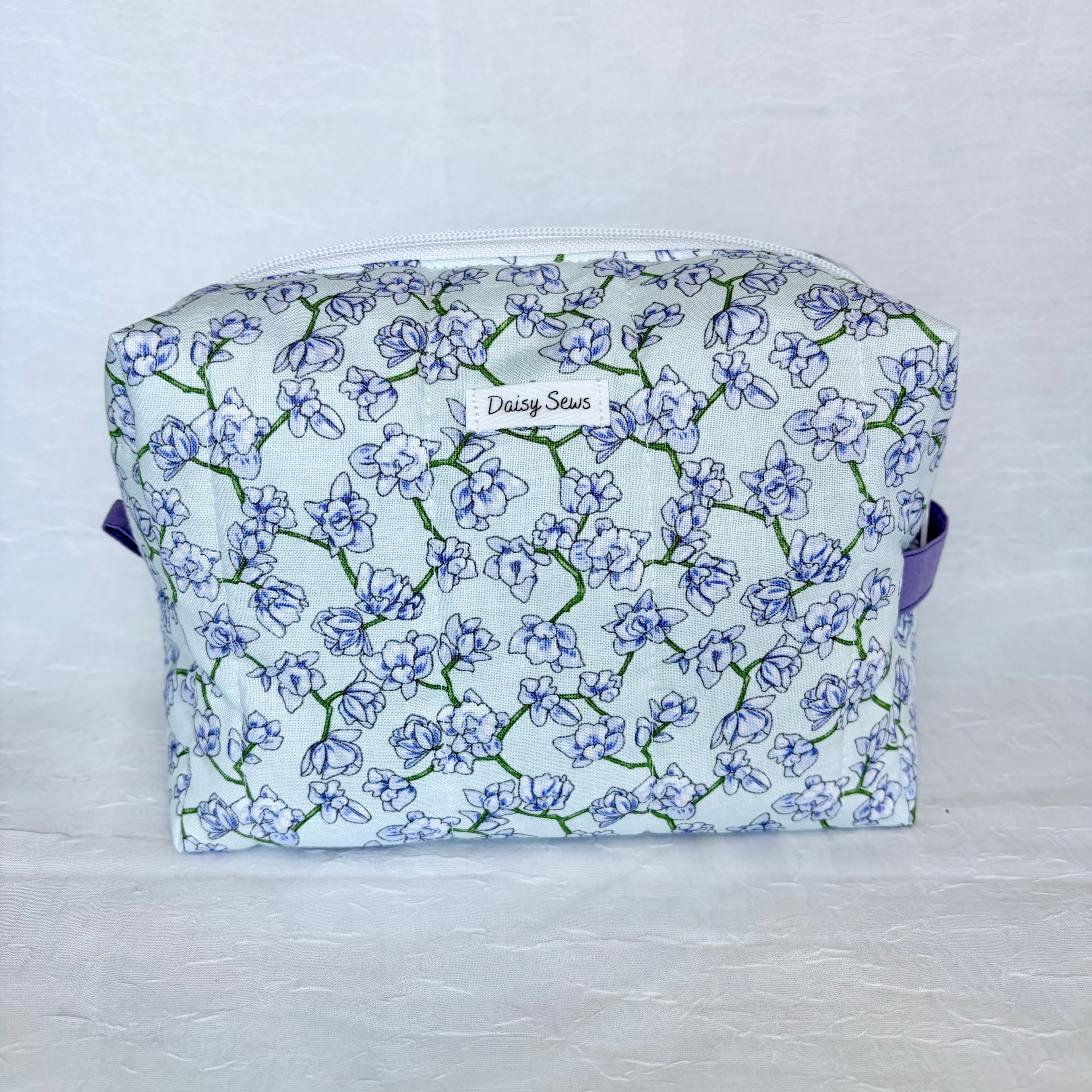 light blue Floral-patterned fabric bag with a visible brand name on a light background
