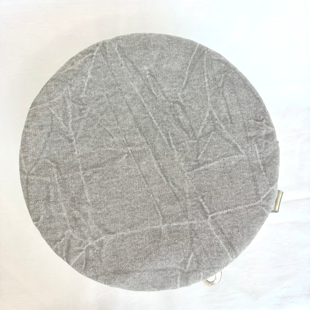 A round gray fabric-covered stool cushion with a textured, crinkled pattern, shown from a top-down view on a white background.