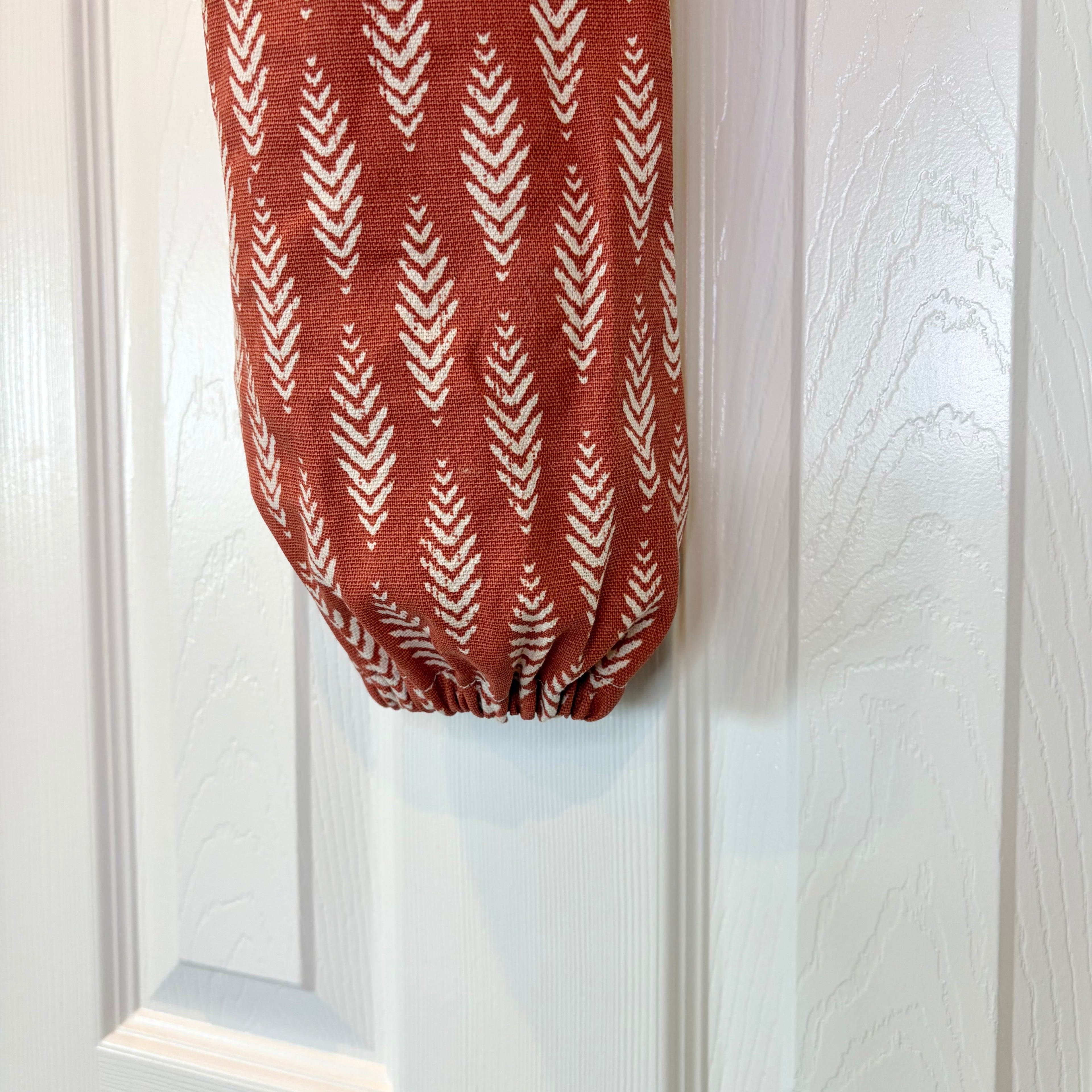 Close up of scrunched up bottom of Orange and White Plastic Bag Organizer against white door