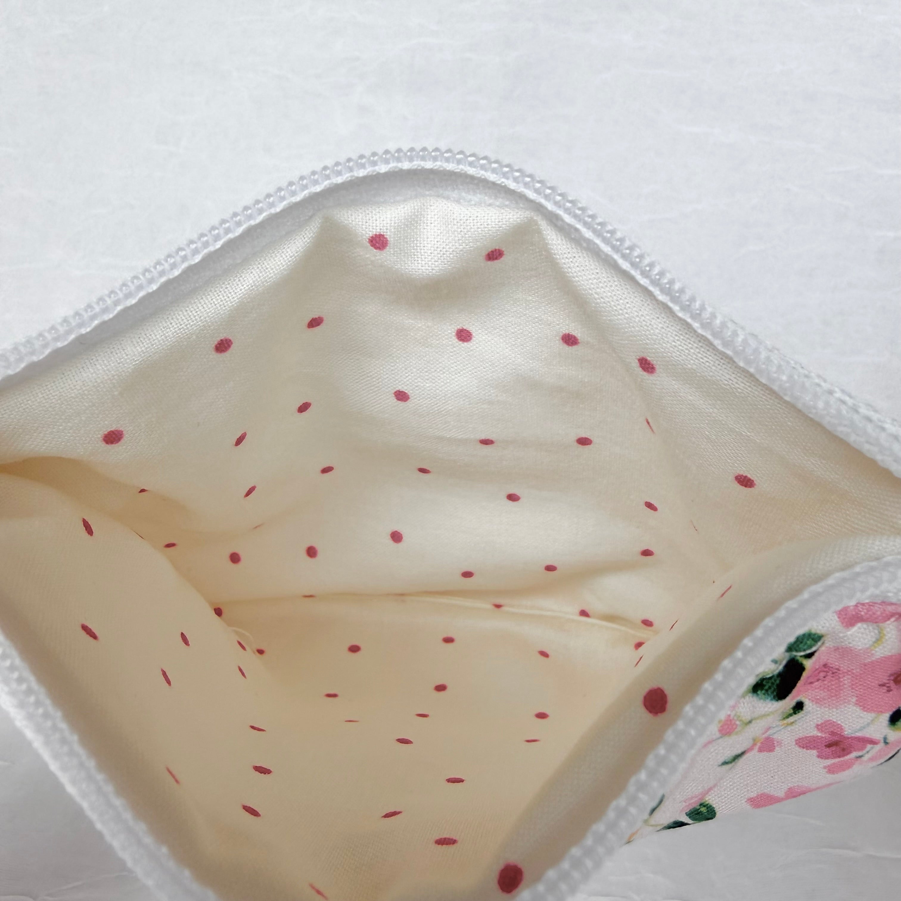 Cream with small pink polka dot interior with whit zipper at top opening on white background