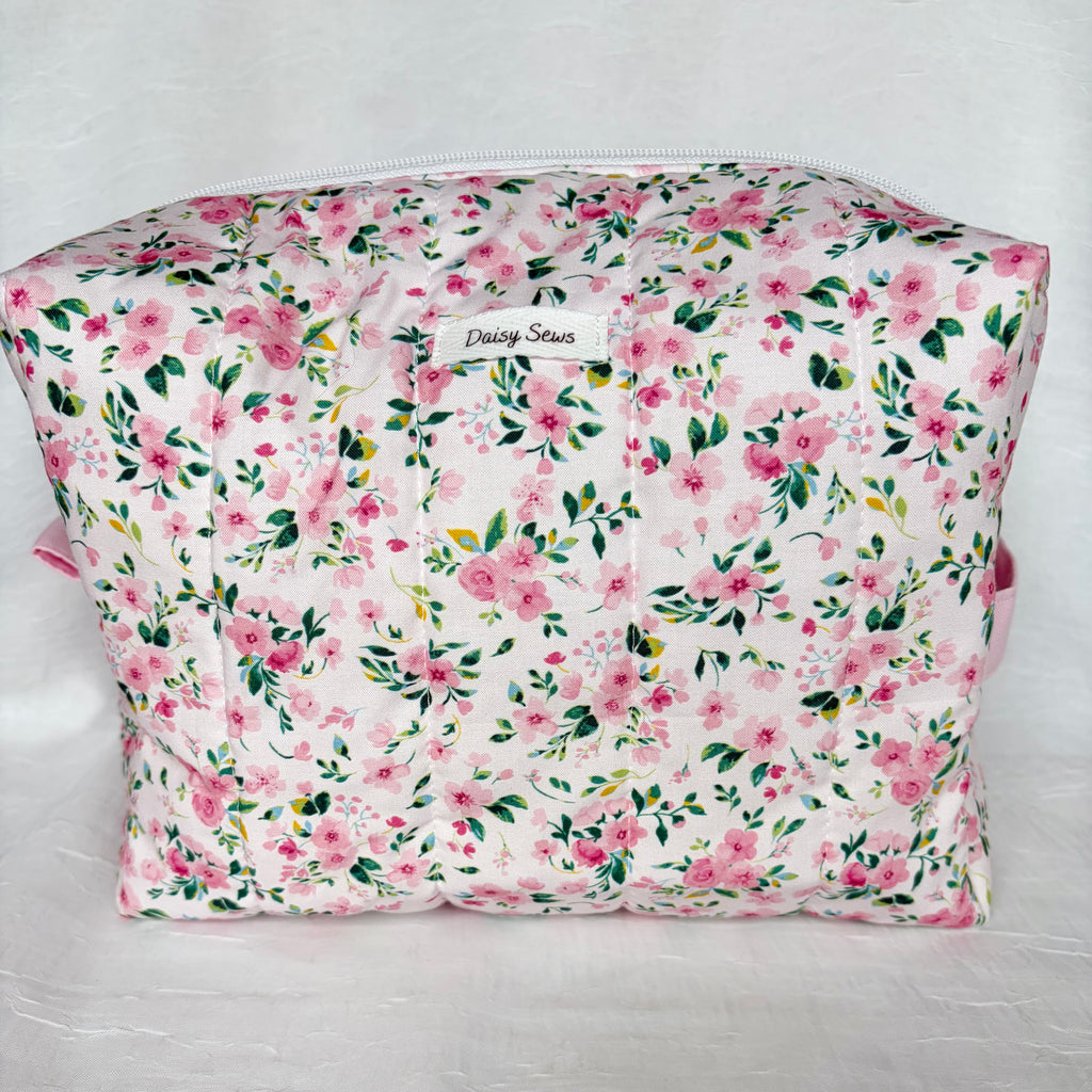 pink and green floral boxy bag with white label and zipper on white background