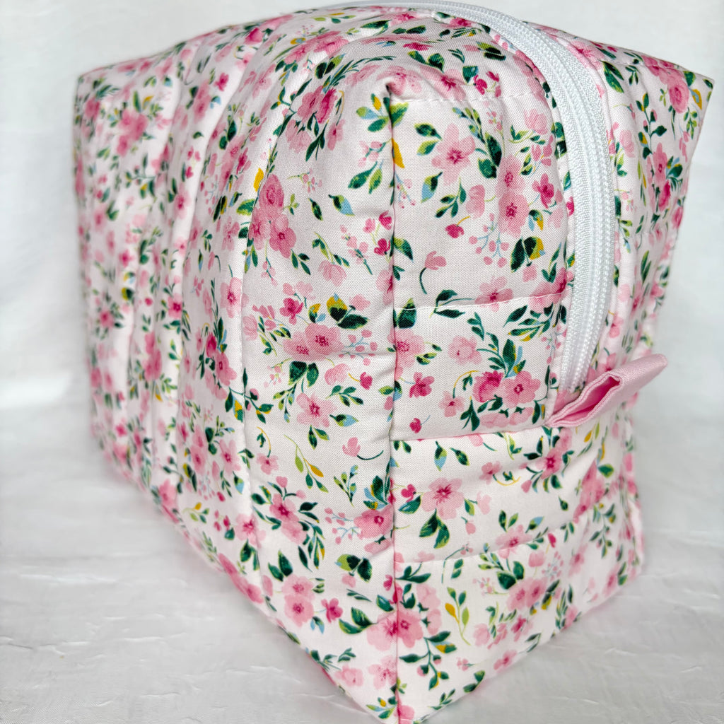 side view of light pink pull tab and white zipper on pink and green floral boxy bag on white background