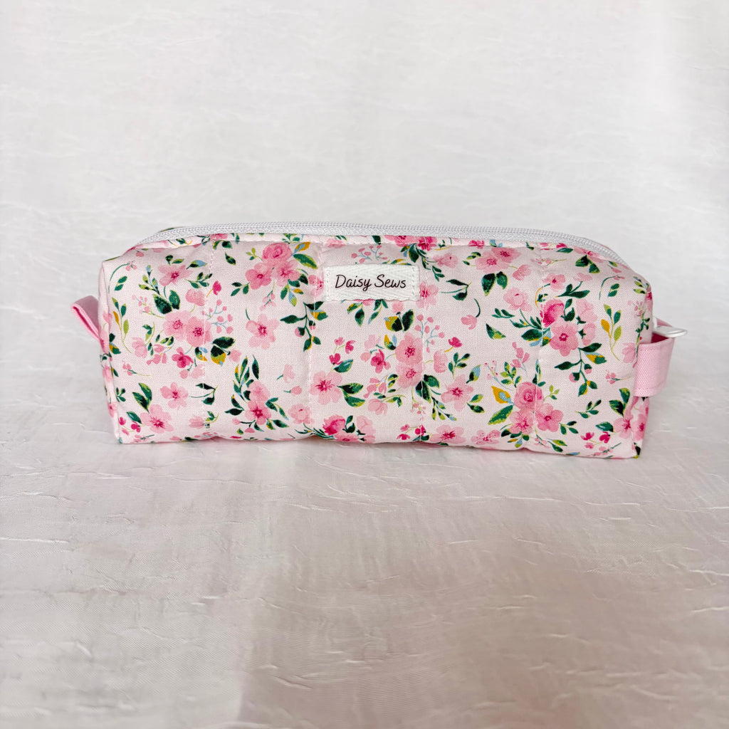 Pink Floral with green leaf patterned boxy bag with light pink pull tab and handle against white background