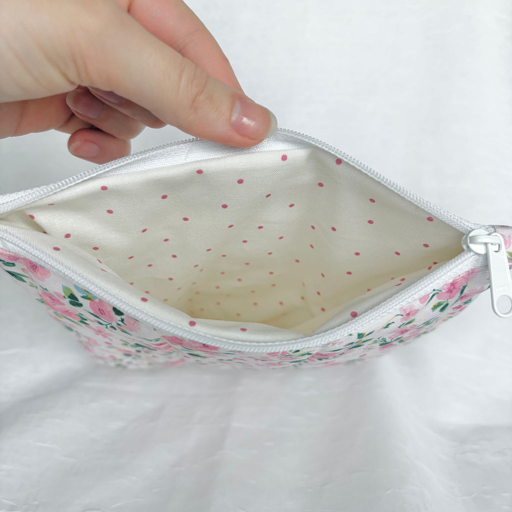 cream with small pink polka dot interior with white zipper at top opening on white background