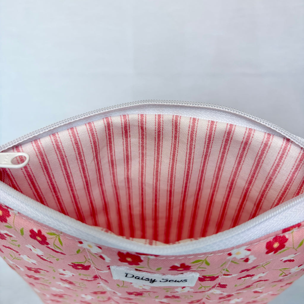 Pink floral pouch with a red striped lining on a white background